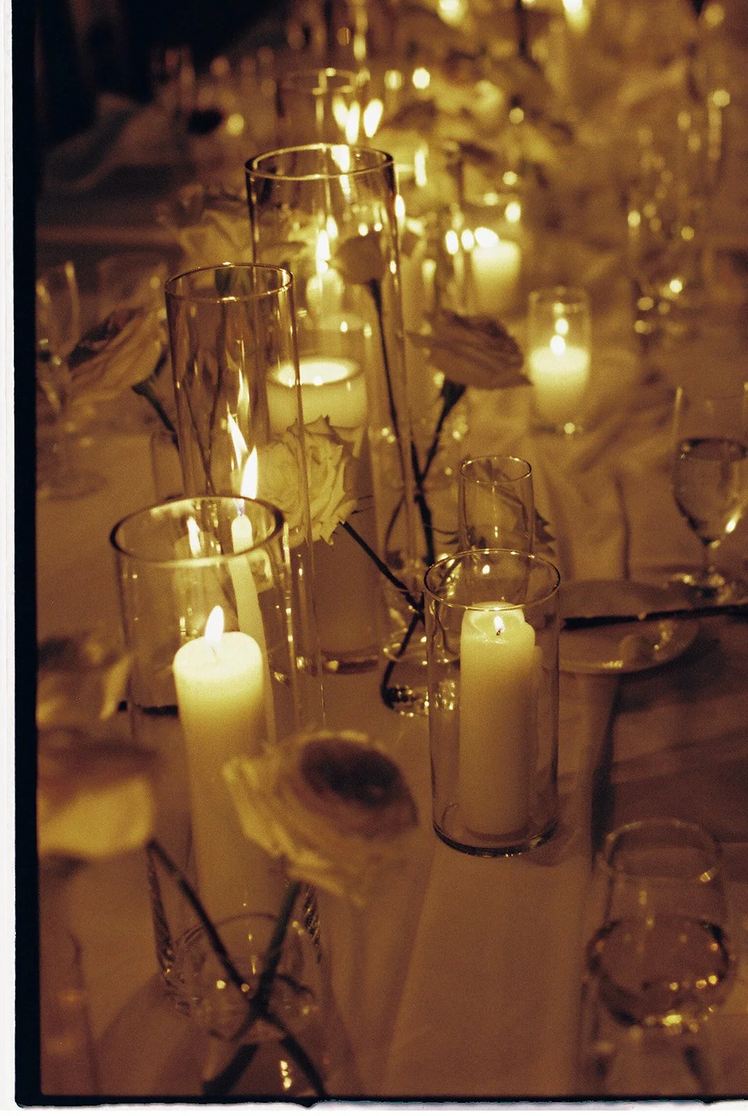 The dinner table arranged with candles, white roses and ranunculus.