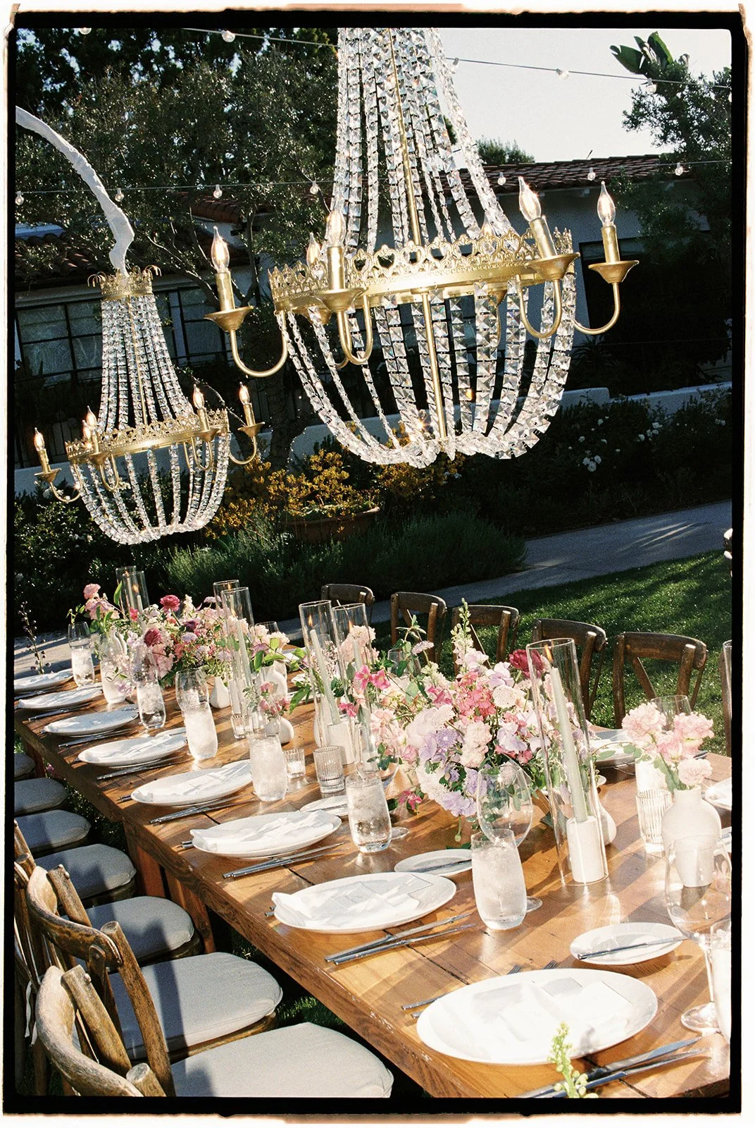 Gold accented chandeliers hang over the floral and candle lined tables. 35 mm film. 
