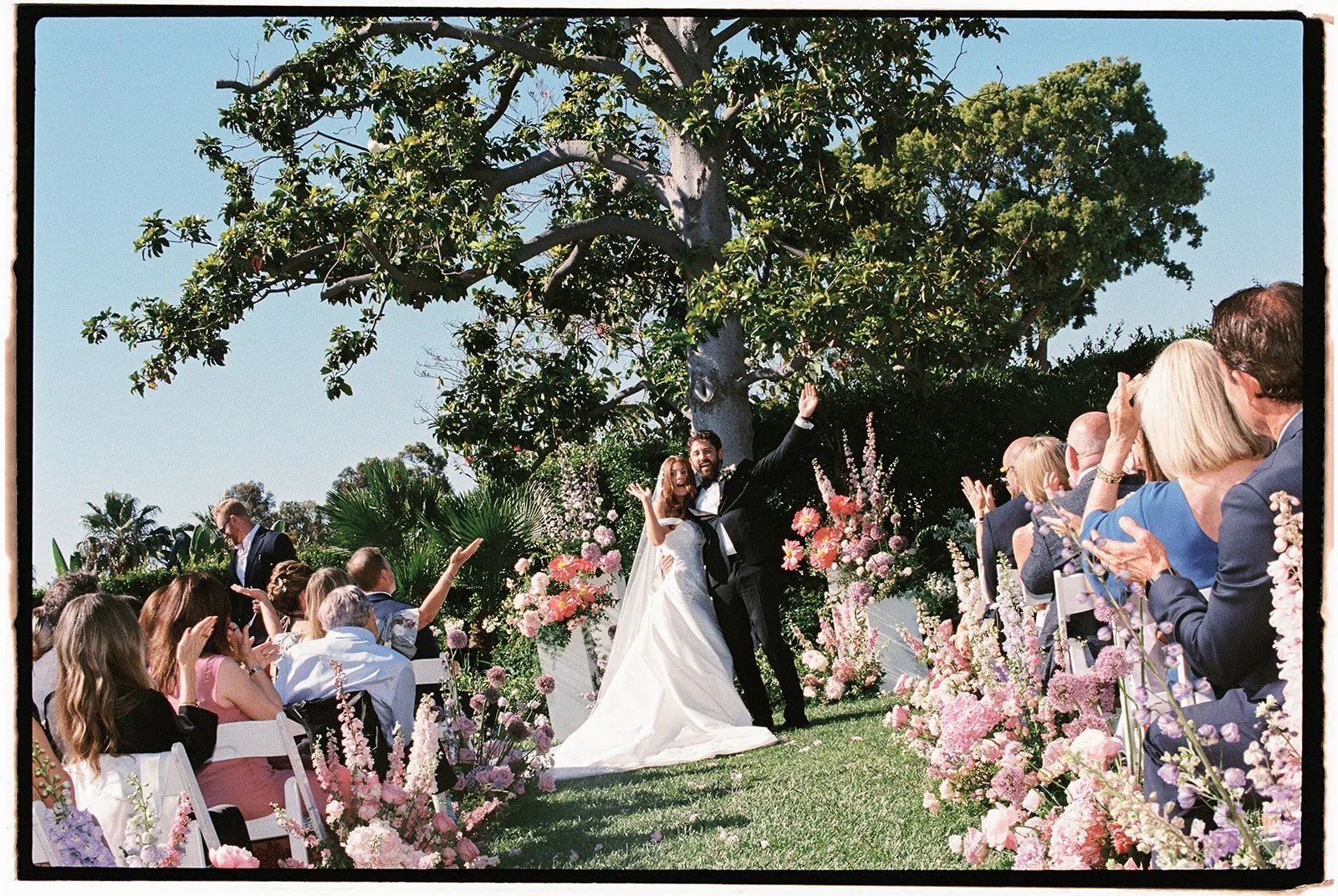  The bride and groom looking out at their loved ones as everyone cheers. 35 mm film. 