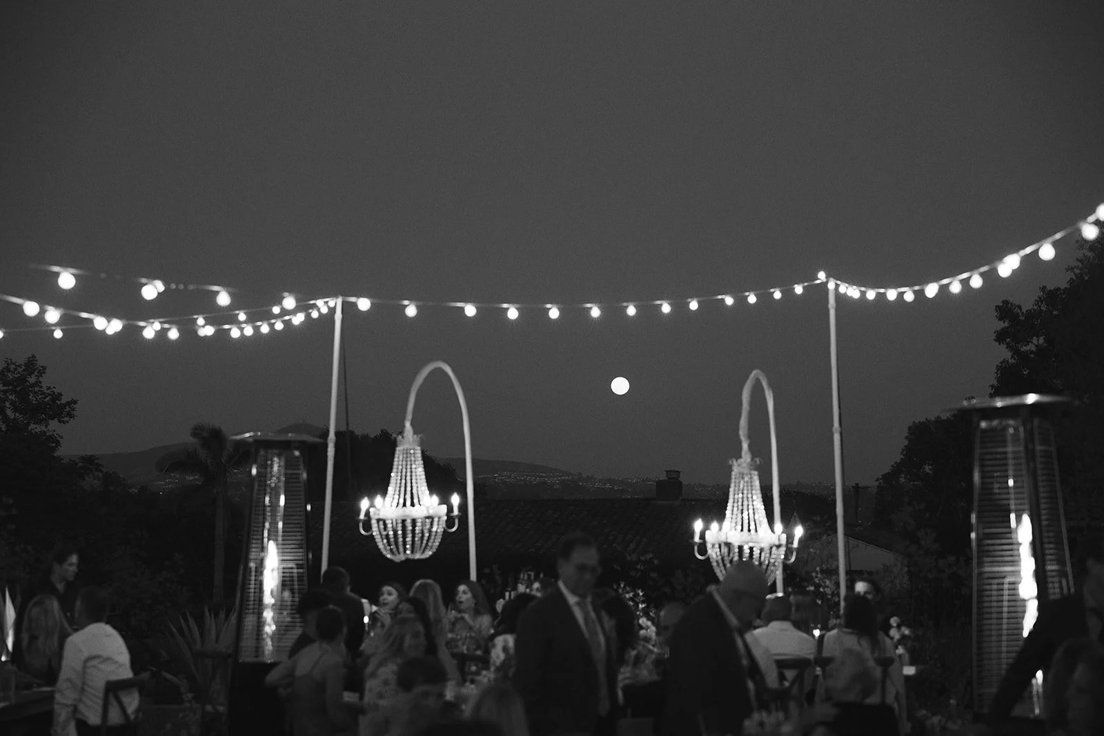  The moon shines bright between dangling chandeliers. Digital. 