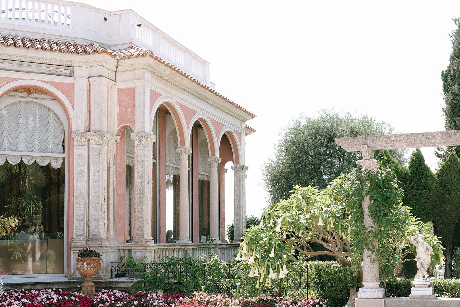 The Villa Ephrussi de Rothschild surrounded by vibrant colorful florals and plants and marble statues in the South of France