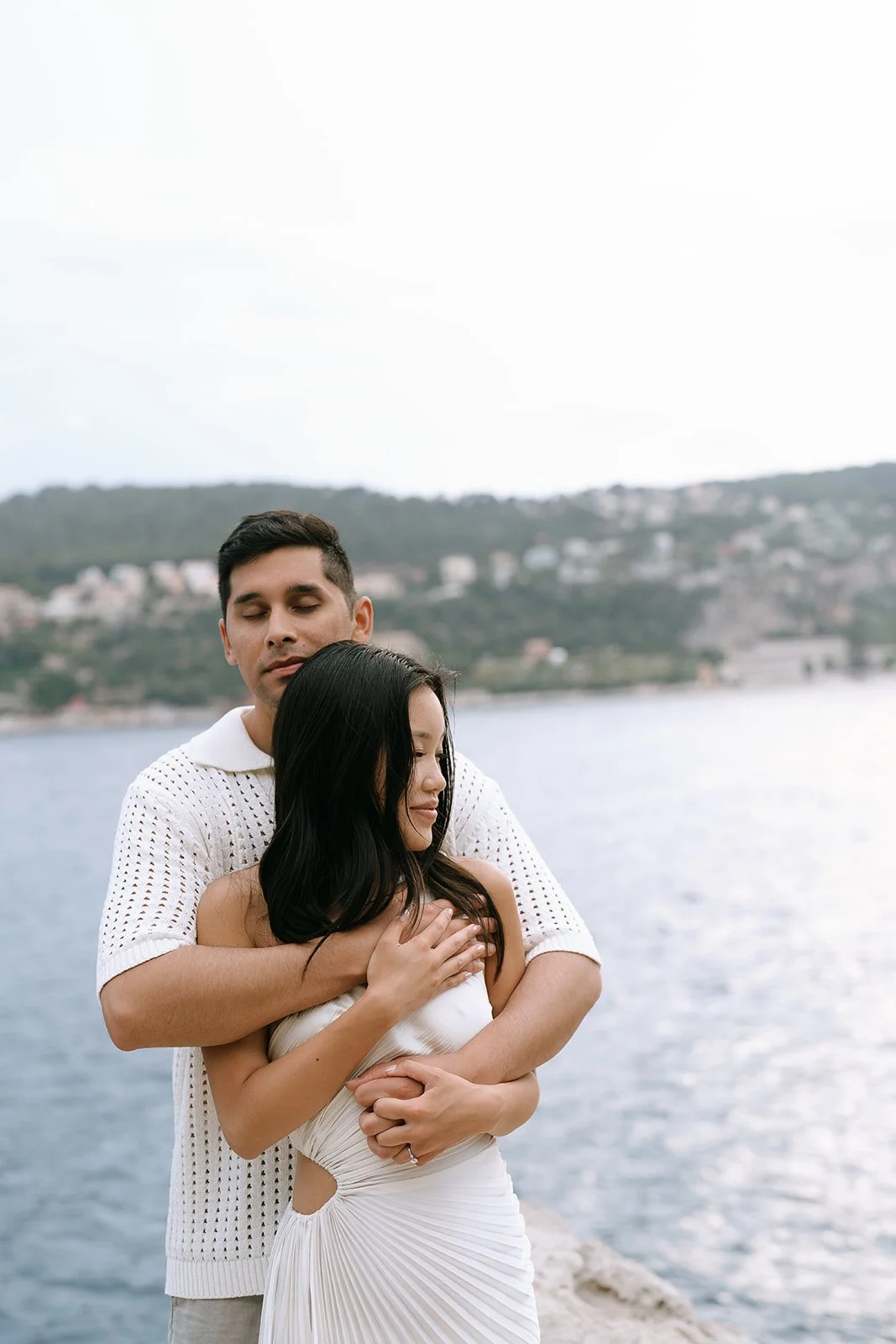 Couple standing together overlooking the Bay of Villefranche in the Mediterranean Sea on the French Riviera during their destination engagement photoshoot