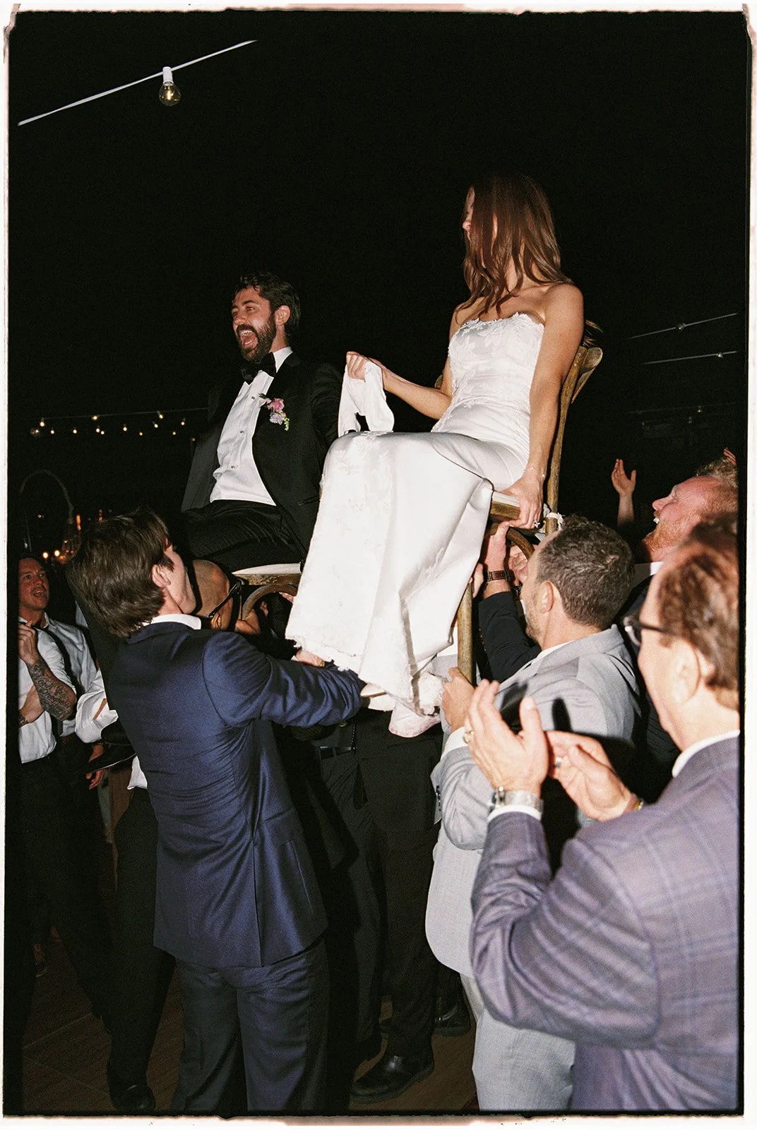  The bride and groom are lifted up by their friends and family in the traditional Jewish Hora Dance. 35 mm film. 