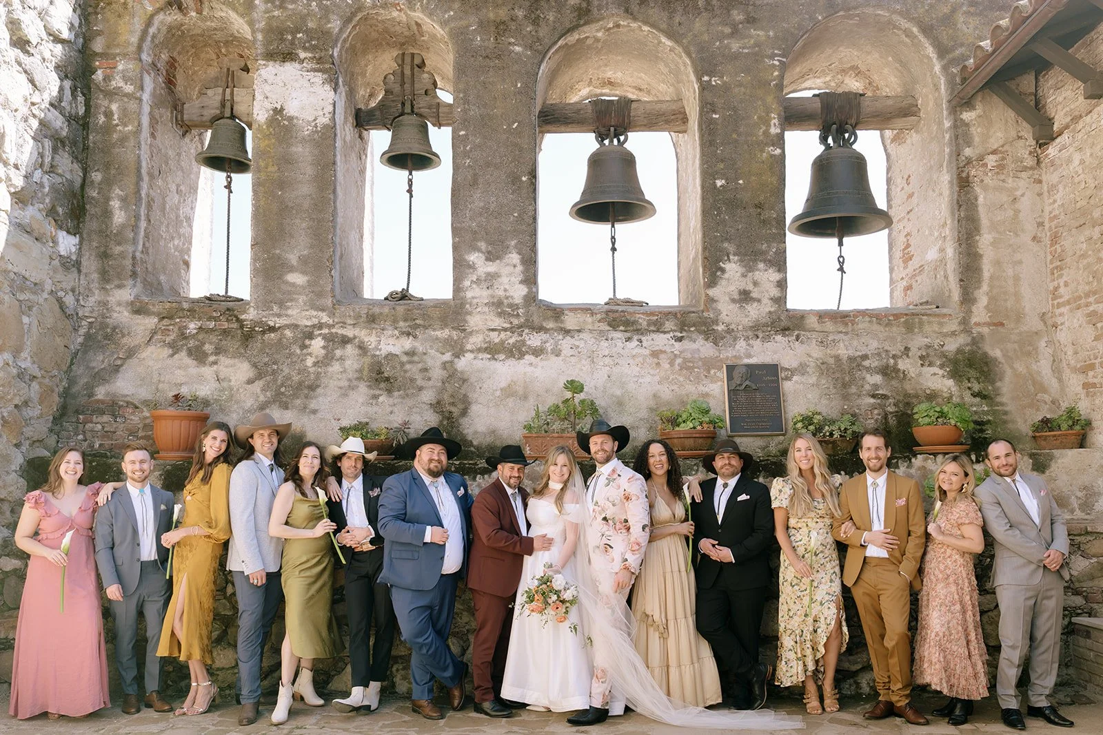 colorful wedding bridal party poses for romantic portraits at the san juan mission