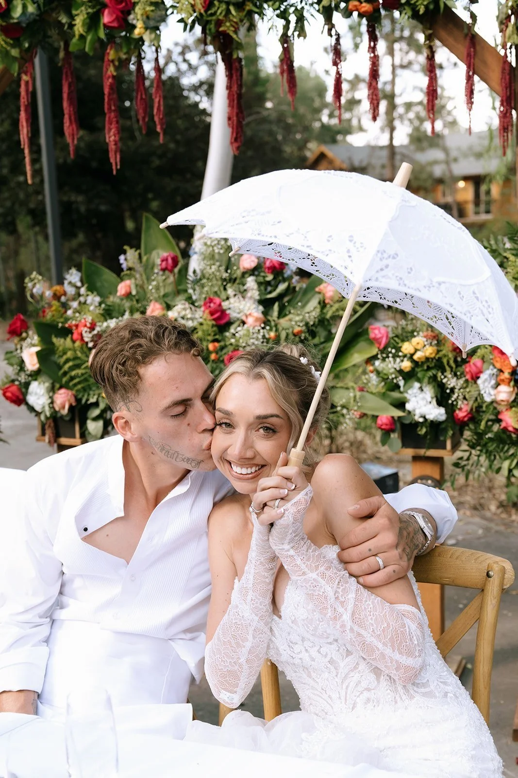 Bride and Groom sitting at the Head table at their outdoor wedding dinner, bride holds a white parasol in Big Bear California