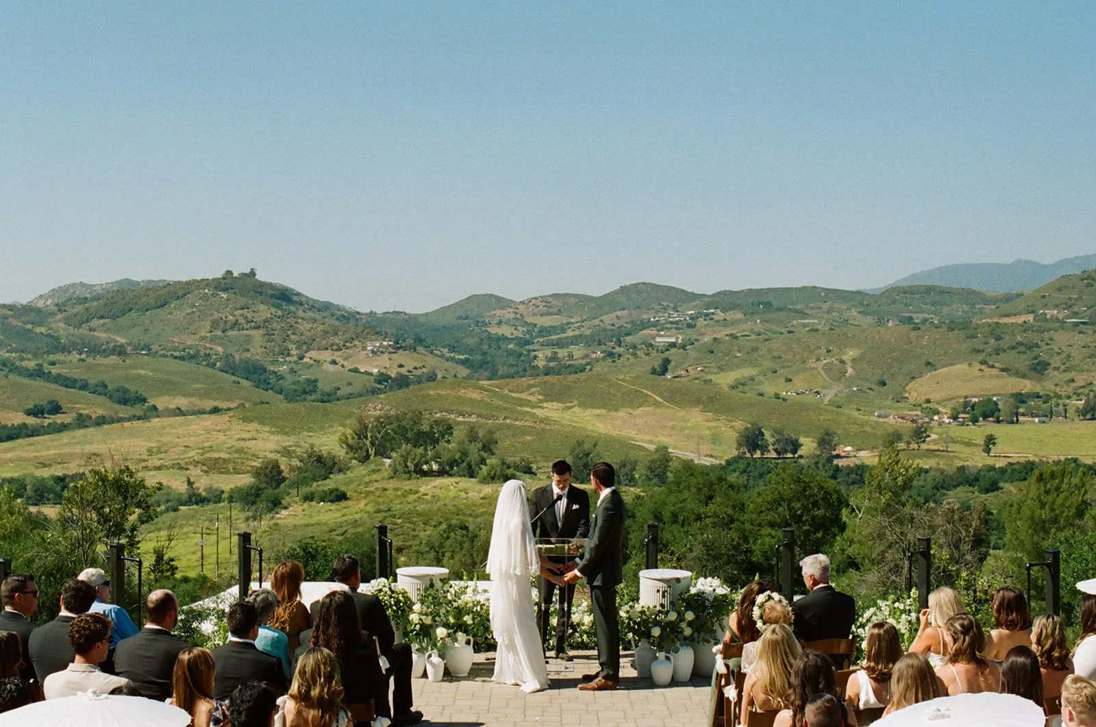 Bride and groom share their vows in front of a canyon view of San Diego. Analog 35 mm film.