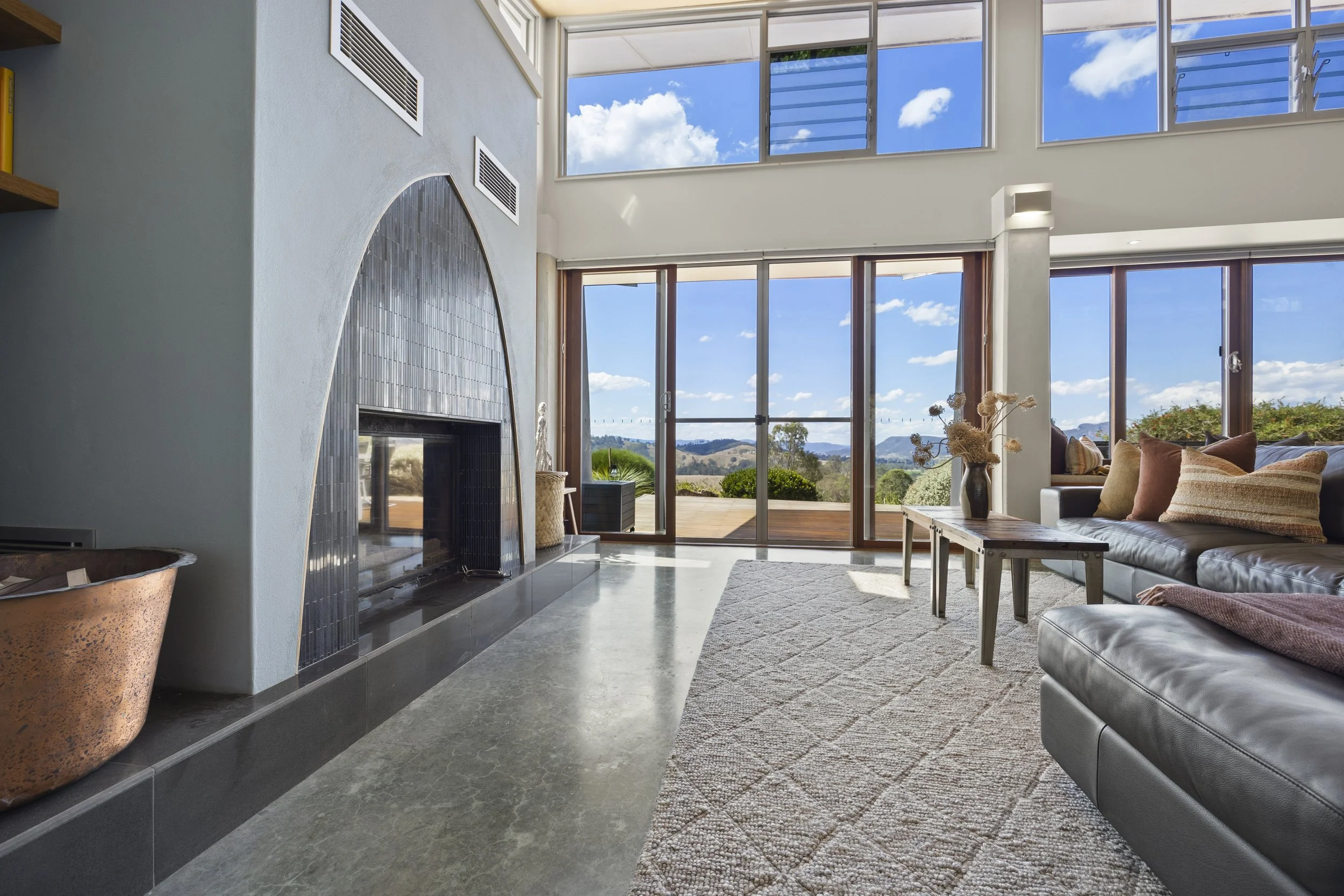Interior living room of an architecturally designed home with large windows, modern fireplace, and scenic landscape views near Gloucester in the Barrington Tops.