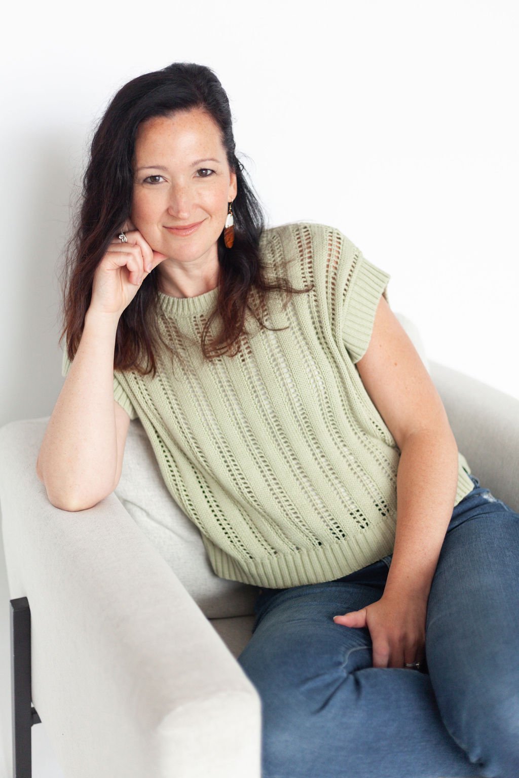Professiona organizer Kara McMillen wearing a green shirt sitting on a grey couch