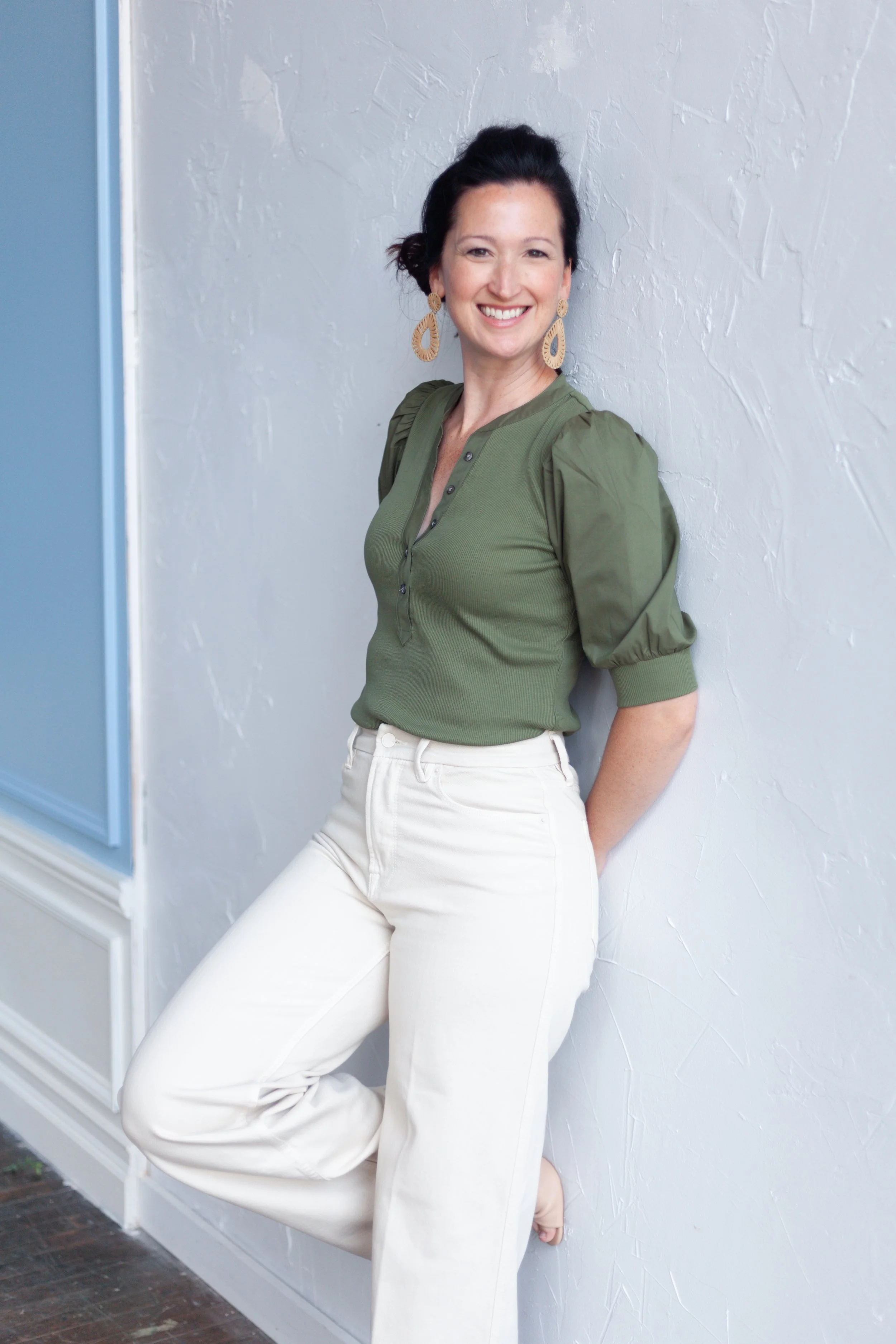 Professiona organizer Kara McMillen wearing a green shirt leaning against a white wall