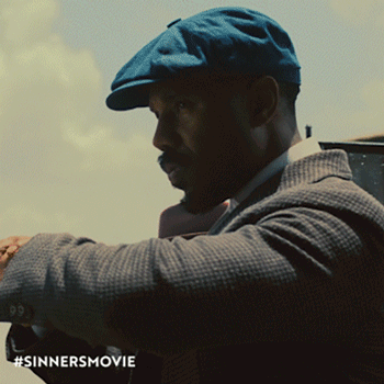 Gif of Michael B. Jordan from the movie “Sinners,” in which he plays twin brothers. The clip shows a camera pan across Michael B. Jordan as both brothers. One is preparing a cigarette and the other is looking at his watch and shaking his head.