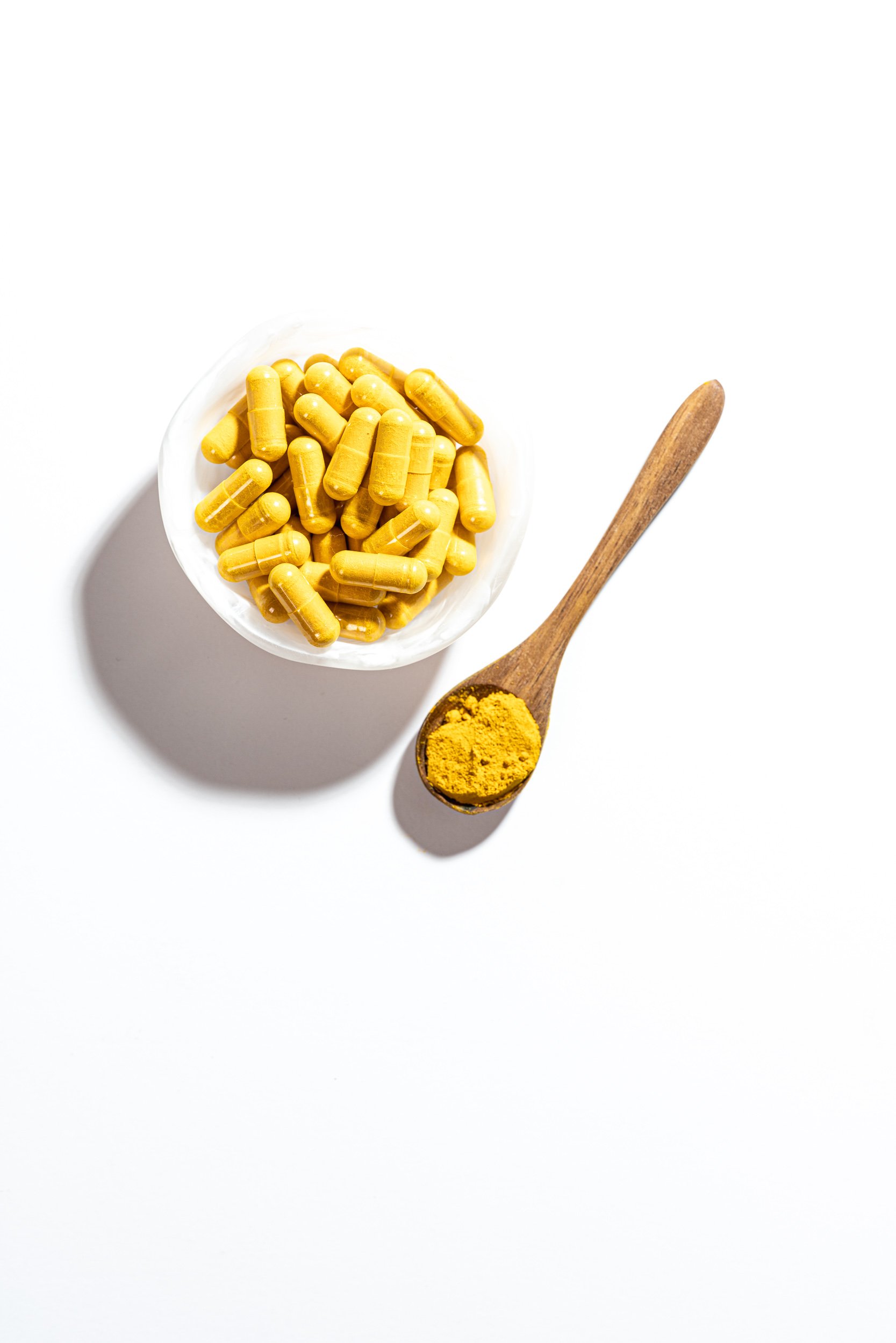 A scenic landscape with green rolling hills, a calm body of water, and tall mountains with some clouds in the sky.