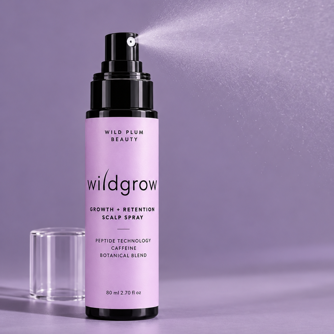 Wild Plum Beauty Wildgrow Growth and Retention Scalp Spray in a lavender bottle against a muted purple-grey studio background.