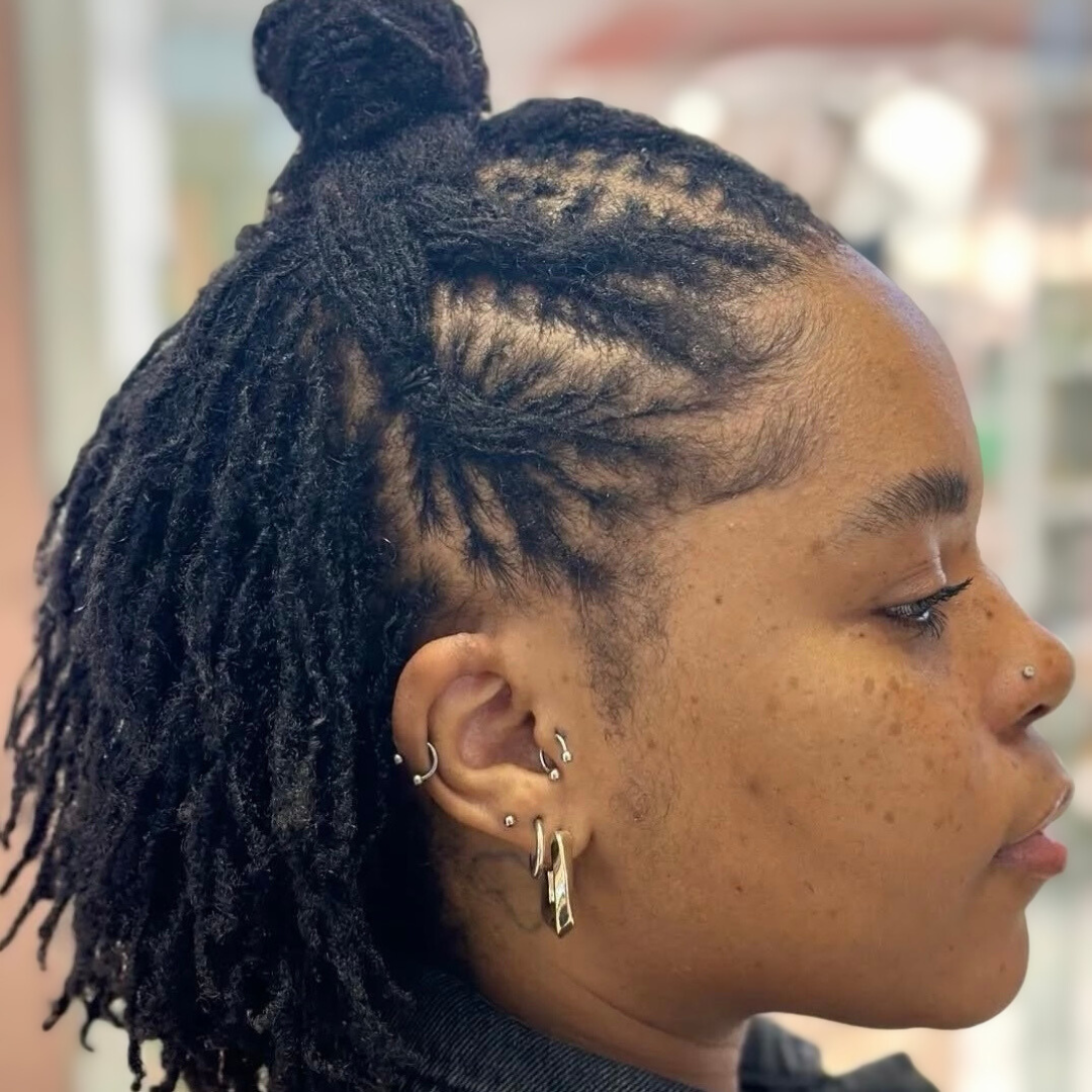 woman with microlocs and braided half up knot bun