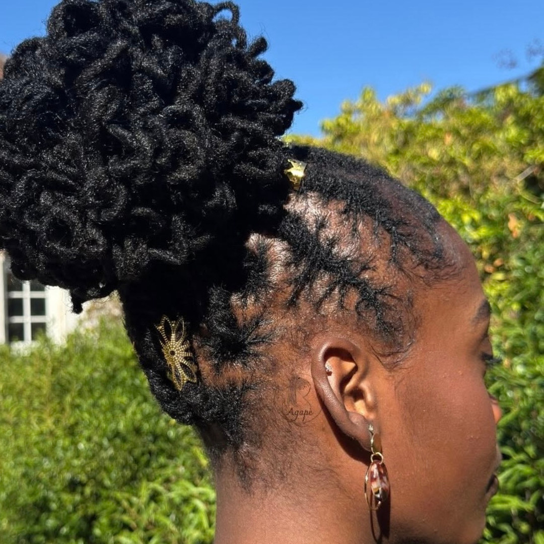 woman with microlocs and flat twists and high curly bun