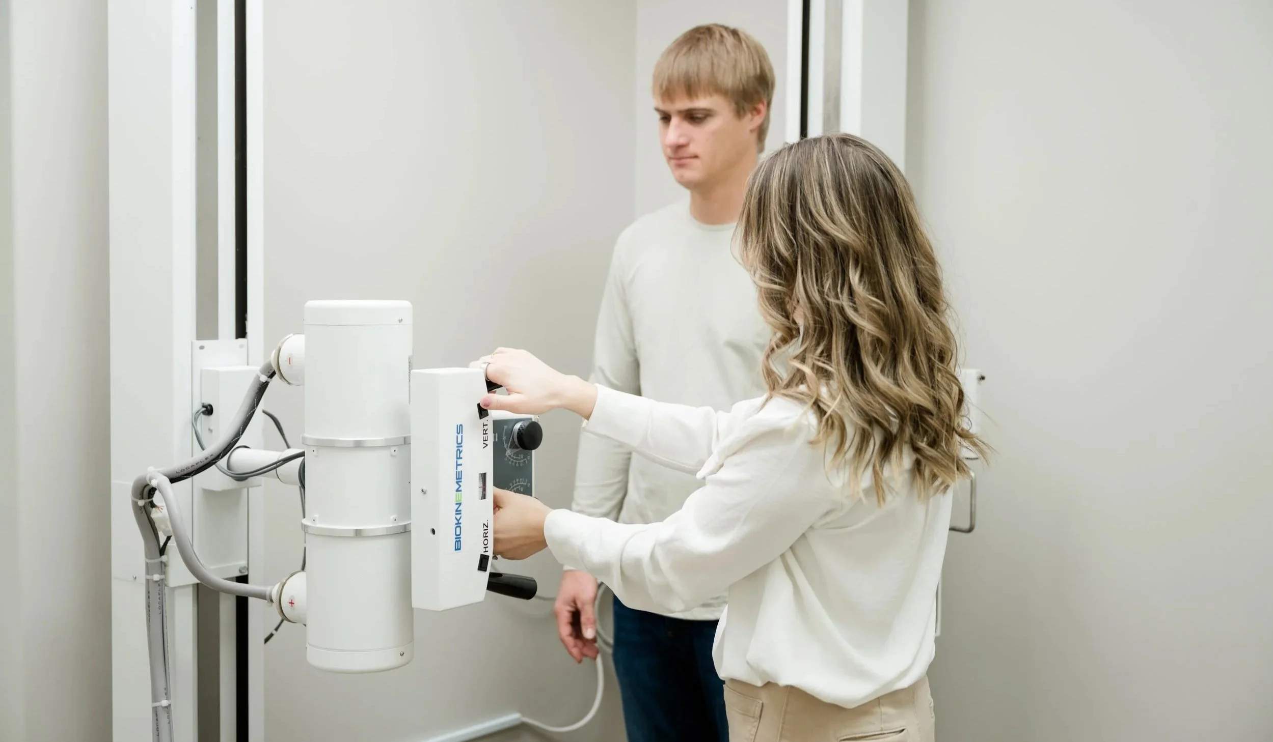 Two people in a medical setting operating a dental X-ray machine.