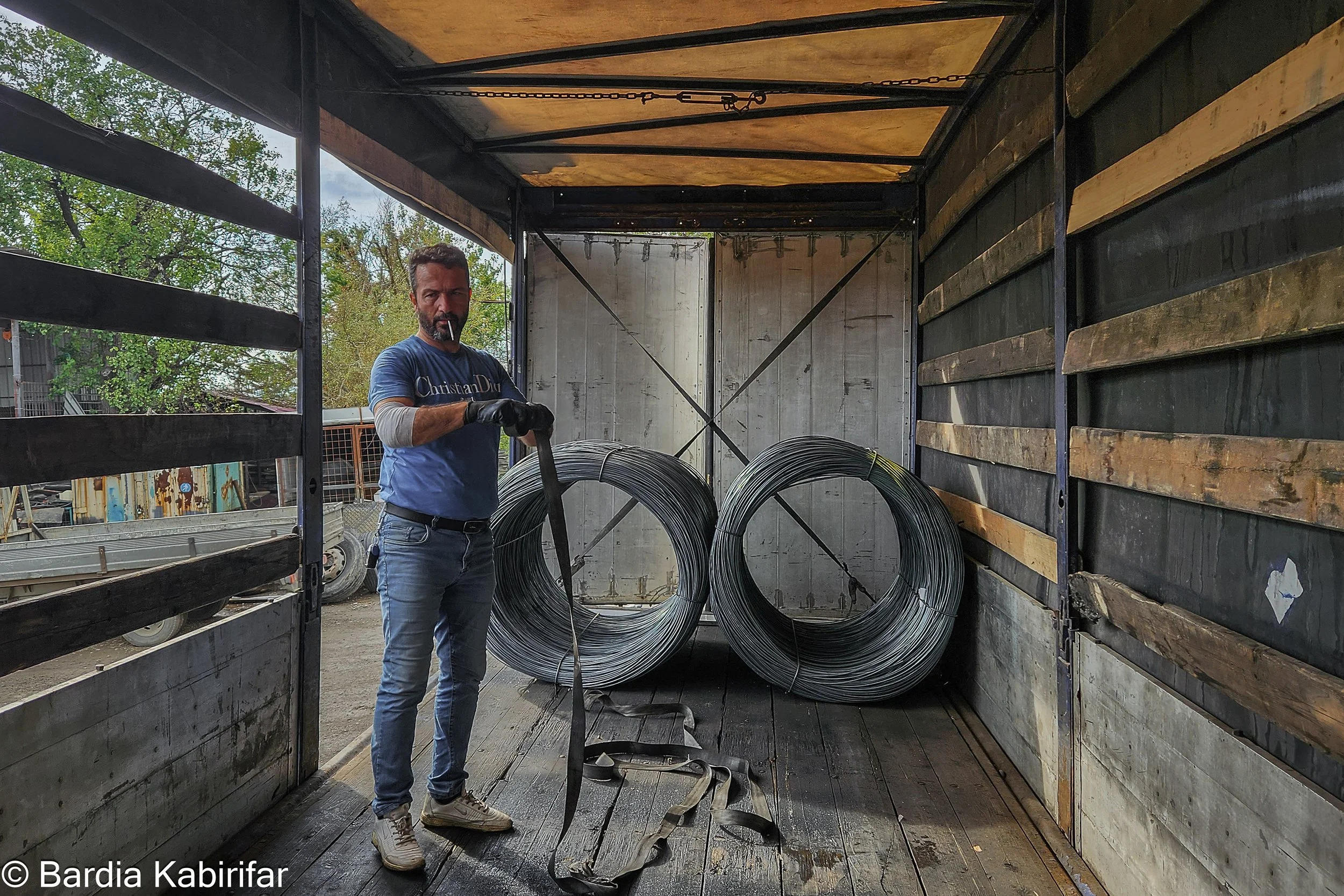 Akbar emptying his trailer after a long journey. His arm was injured a few weeks ago during loading but he couldn't meet a doctor because of constantly being on the road with limited insurance coverage and access to doctor. (October 2nd, 2023 Tbilisi
