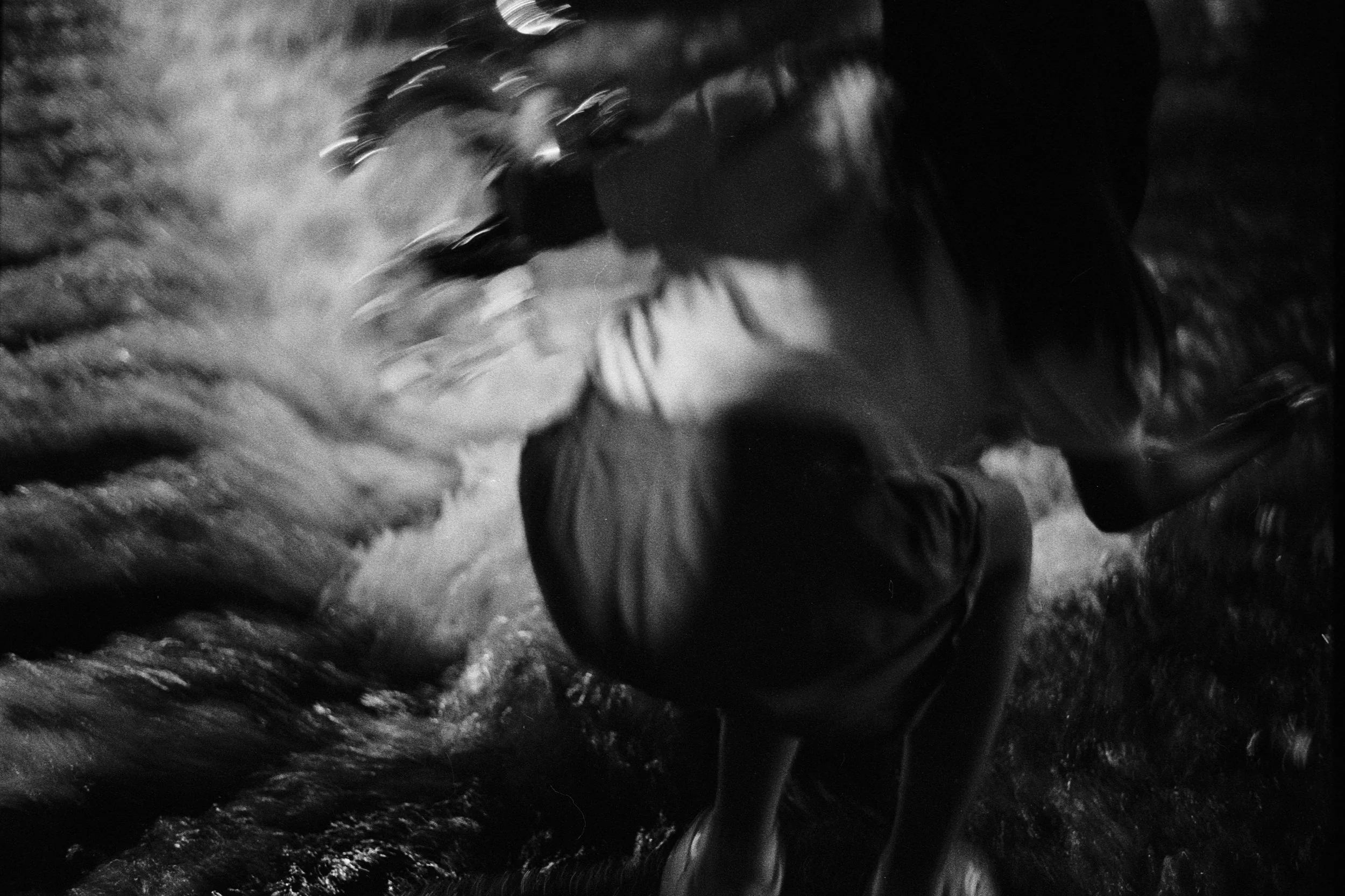 A women playing near the water at night, with motion blur and water splashing around.