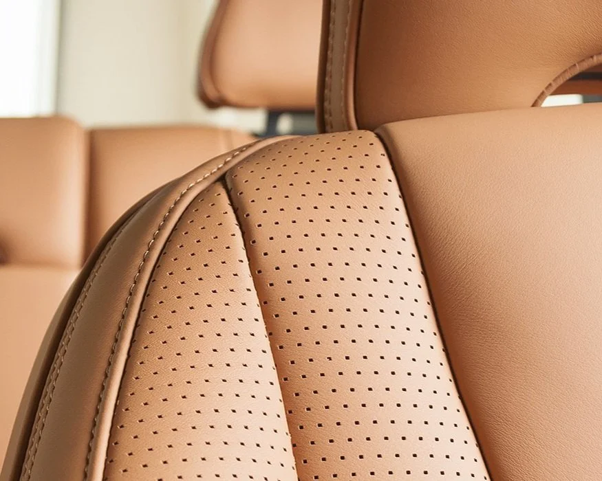 Close-up of a tan leather car seat with perforated detailing and stitching.