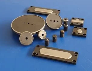 Set of metal mechanical parts including cylinders, blocks, and a circular component on a blue background.