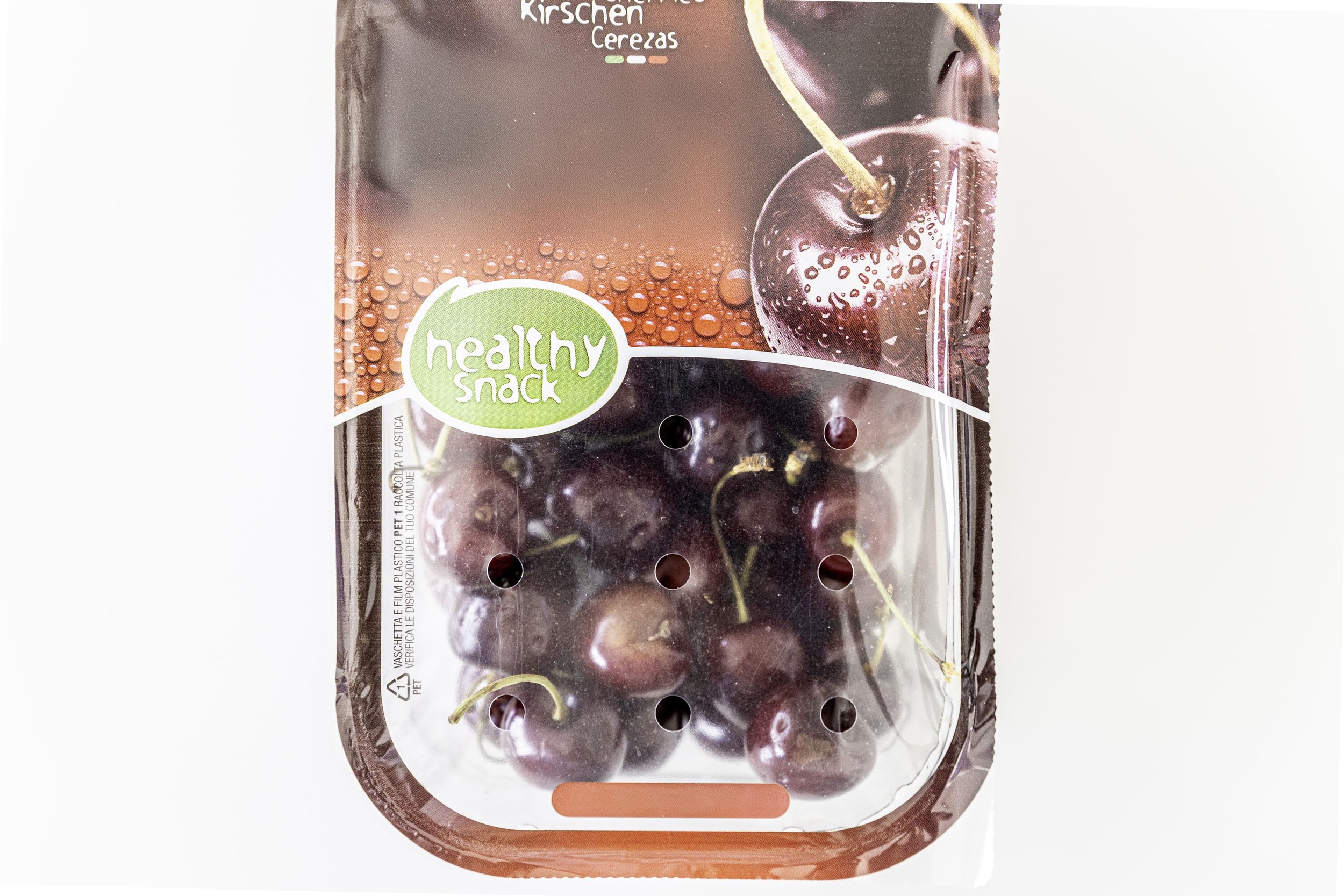 A package of cherry flavored snack food with a clear window showing ripe red cherries inside. The package has a green label reading 'healthy snack' and features images of cherries on the front.