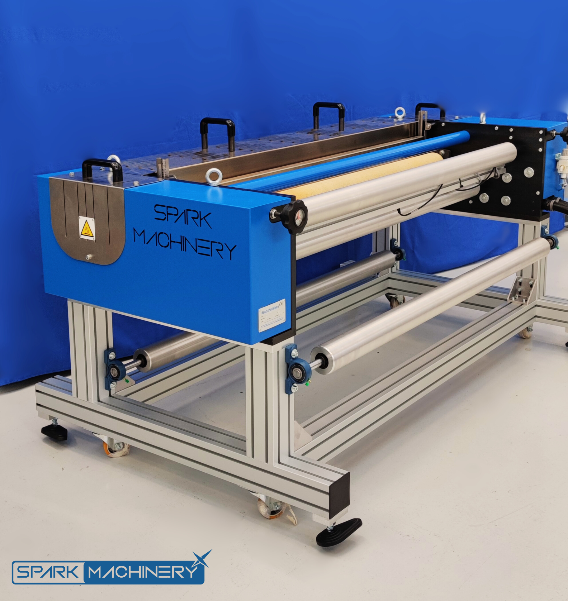 Industrial machinery labeled 'Spark Machinery' with multiple rollers in a bright blue workspace.