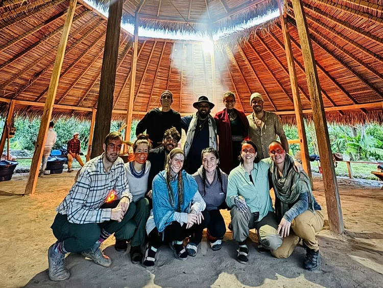 Group posing beneath the timber structure of a thatched roof