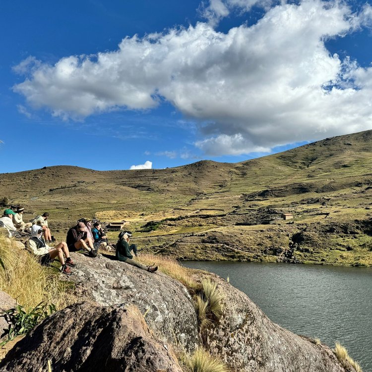 Travellers gathered beside a mountain lake in Peru