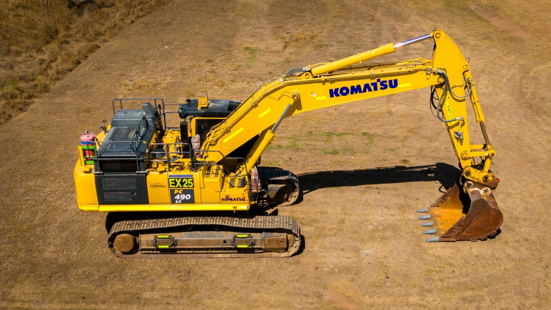 Yellow Komatsu excavator on a construction site with dirt ground.