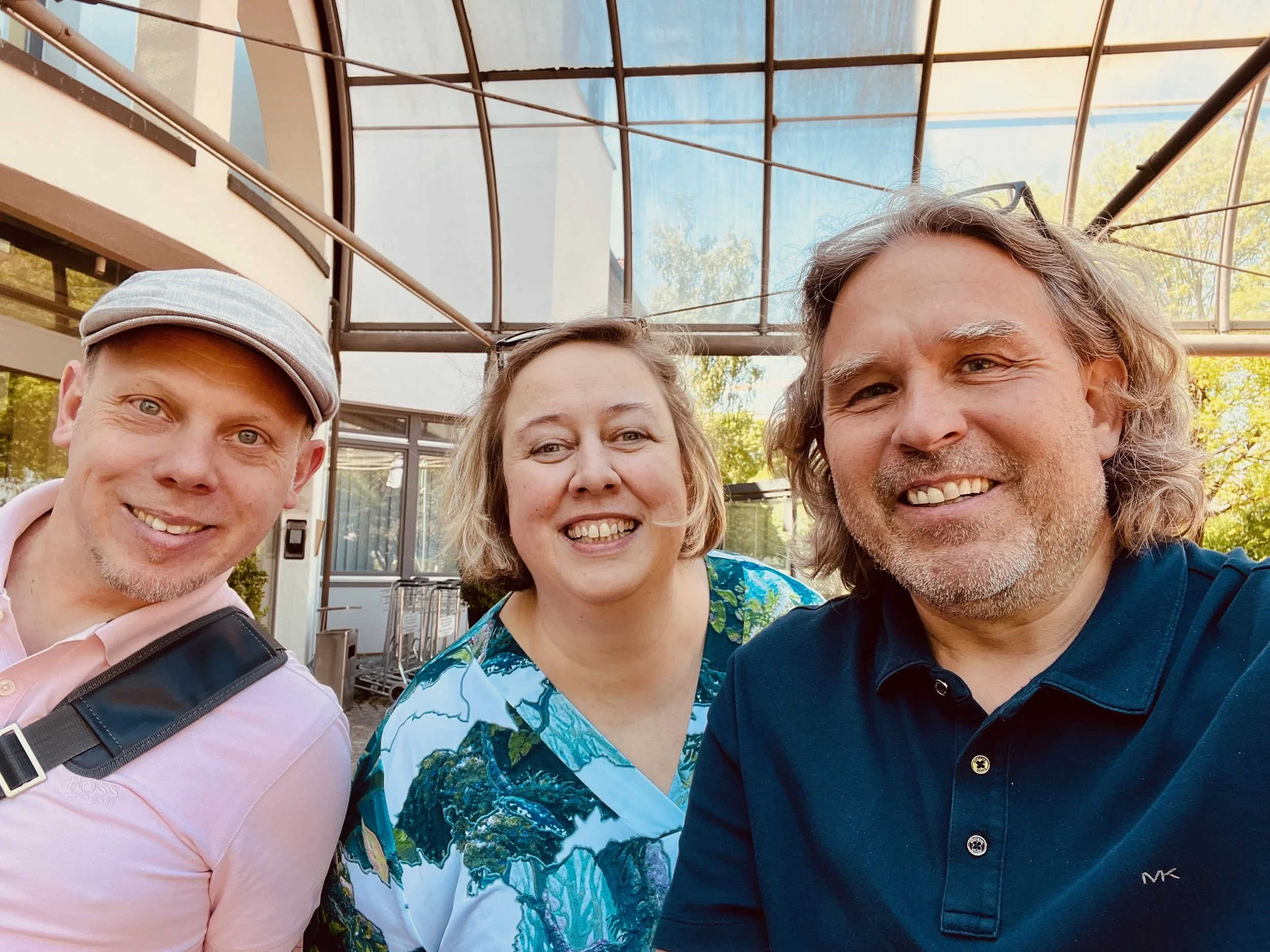 Eine Frau und zwei Männer lächeln in die Kamera, es sieht nach einem spontanen Foto aus