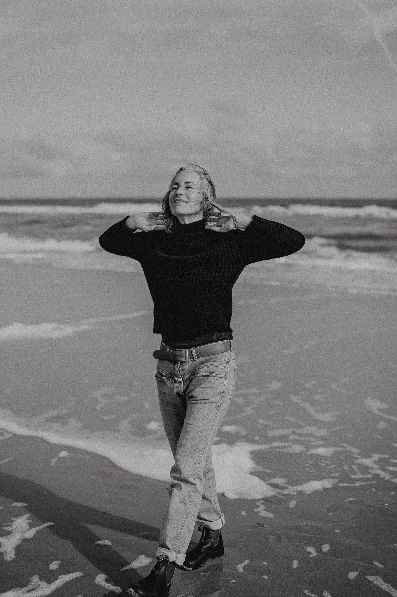 Ein schwarz-weiß Foto einer Frau am Meer, die am Strand entlang läuft. In schwarz-weiß.