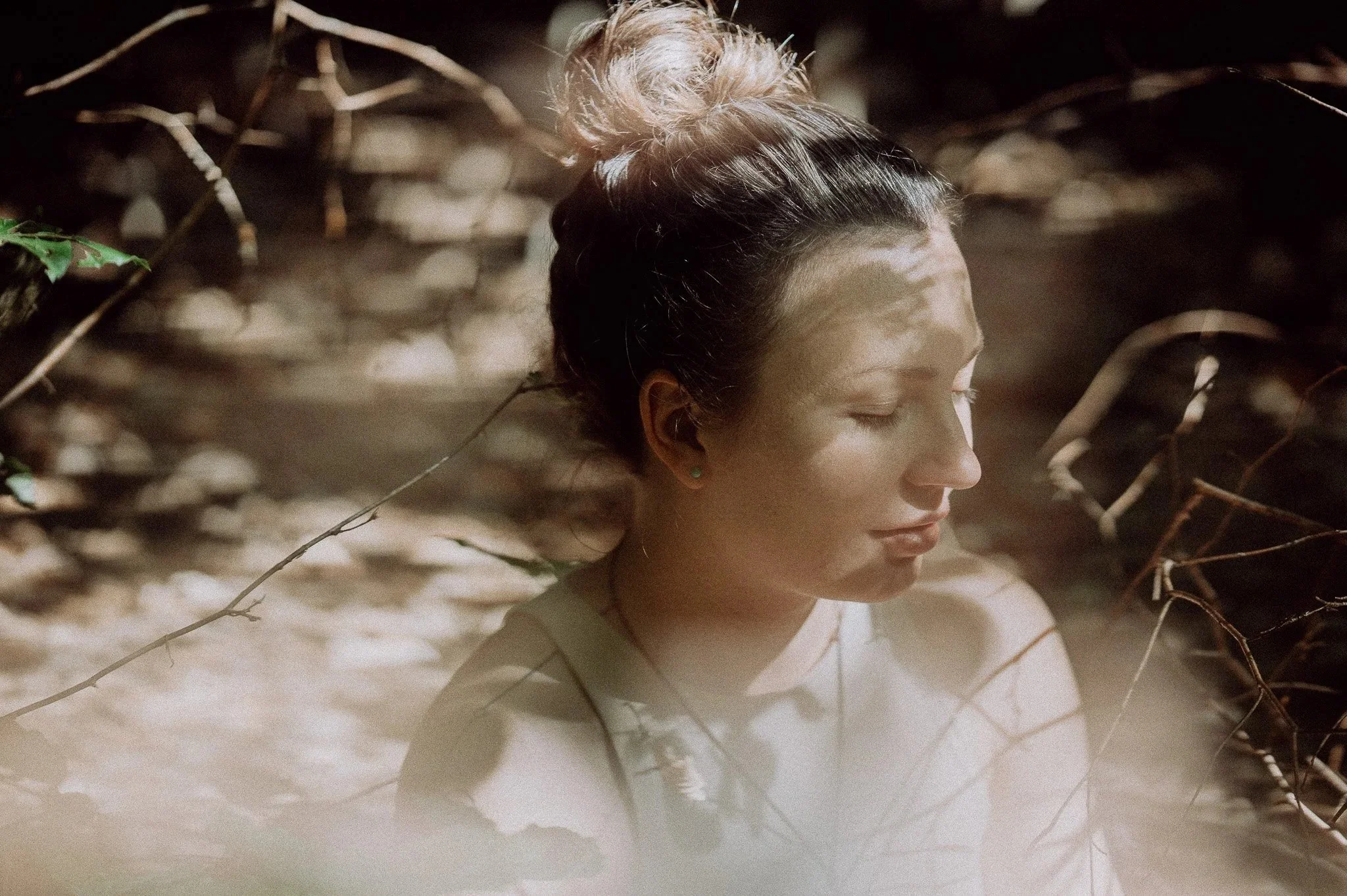 Ein Portrait einer Frau im sanften Licht, um sie herum. Ihre Augen sind geschlossen und ihr Kopf neigt sich nach unten.