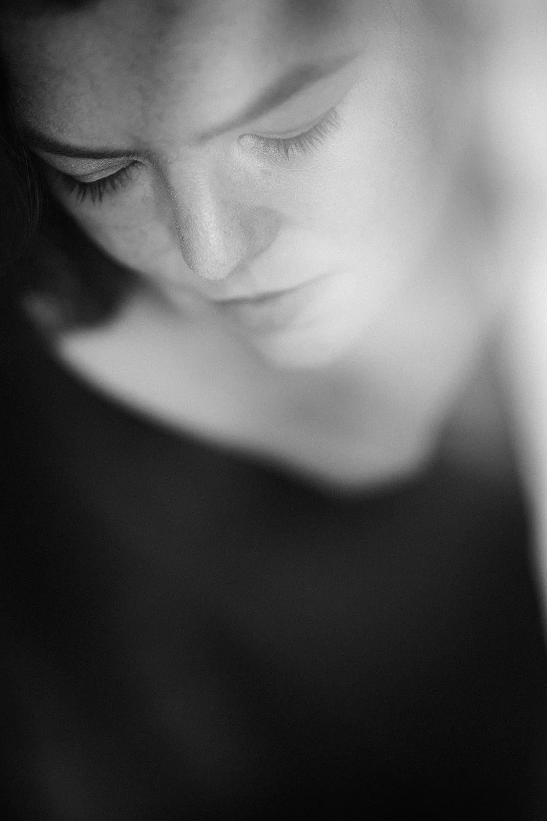 Schwarzweiß Portrait einer Frau, die nach unten blickt.