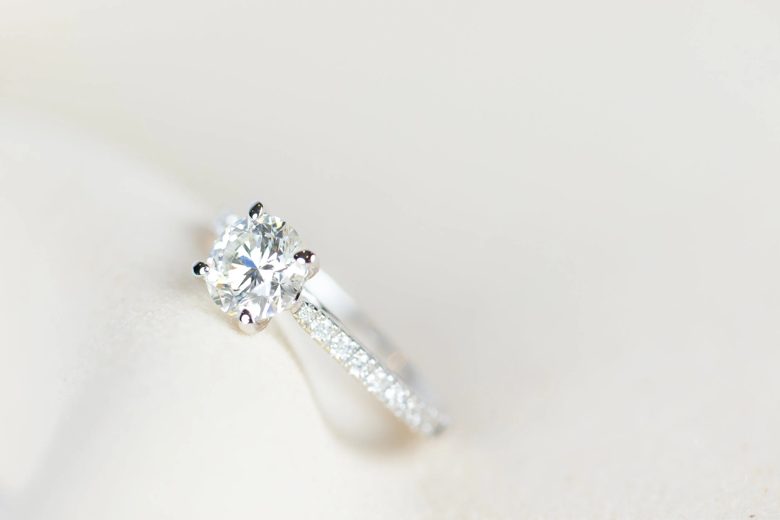 Diamanten verlovingsring met een grote centrale diamant en een band met kleinere diamanten, op een witte achtergrond.