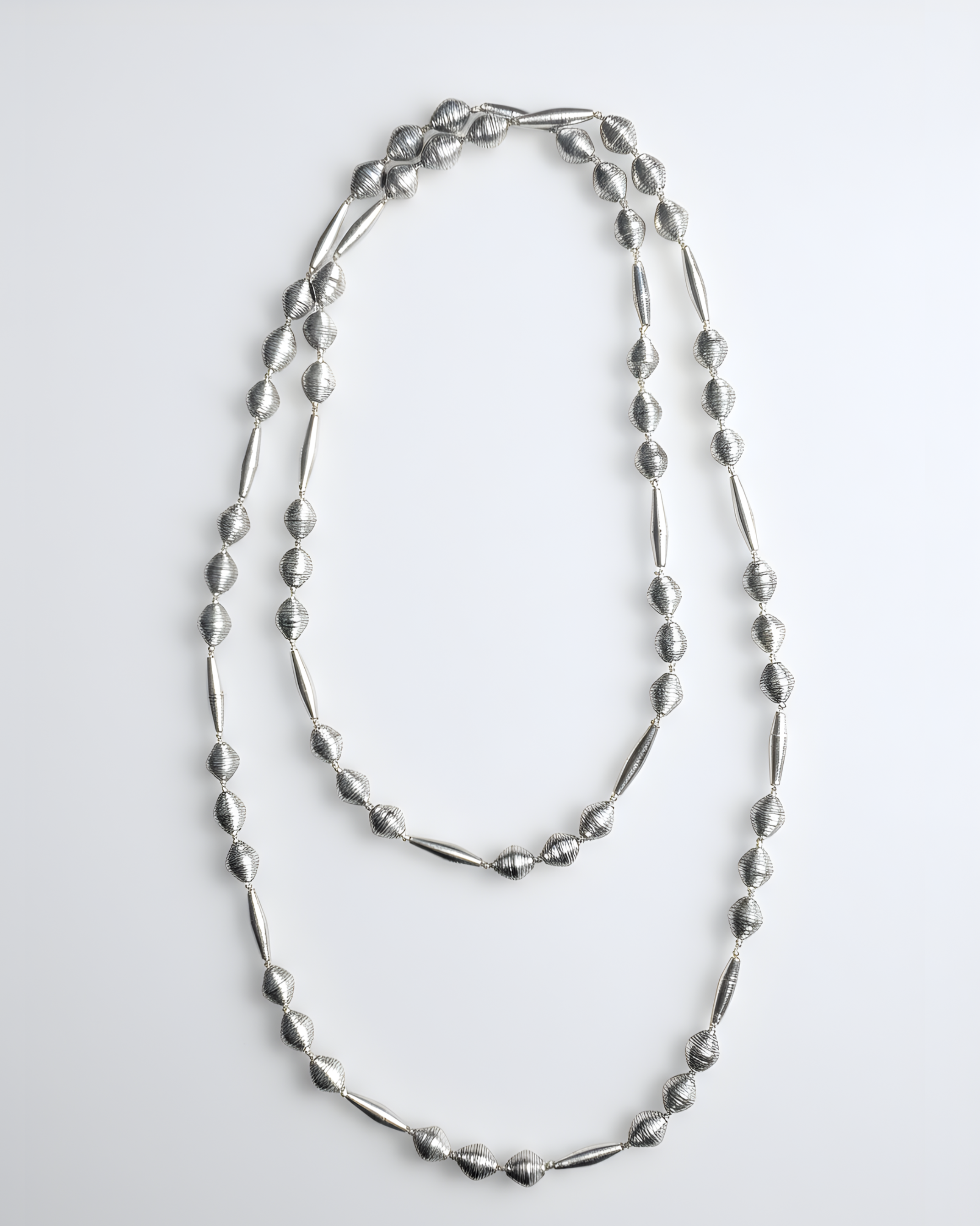 Collana lunga con grandi perle e elementi cilindrici in metallo lucido