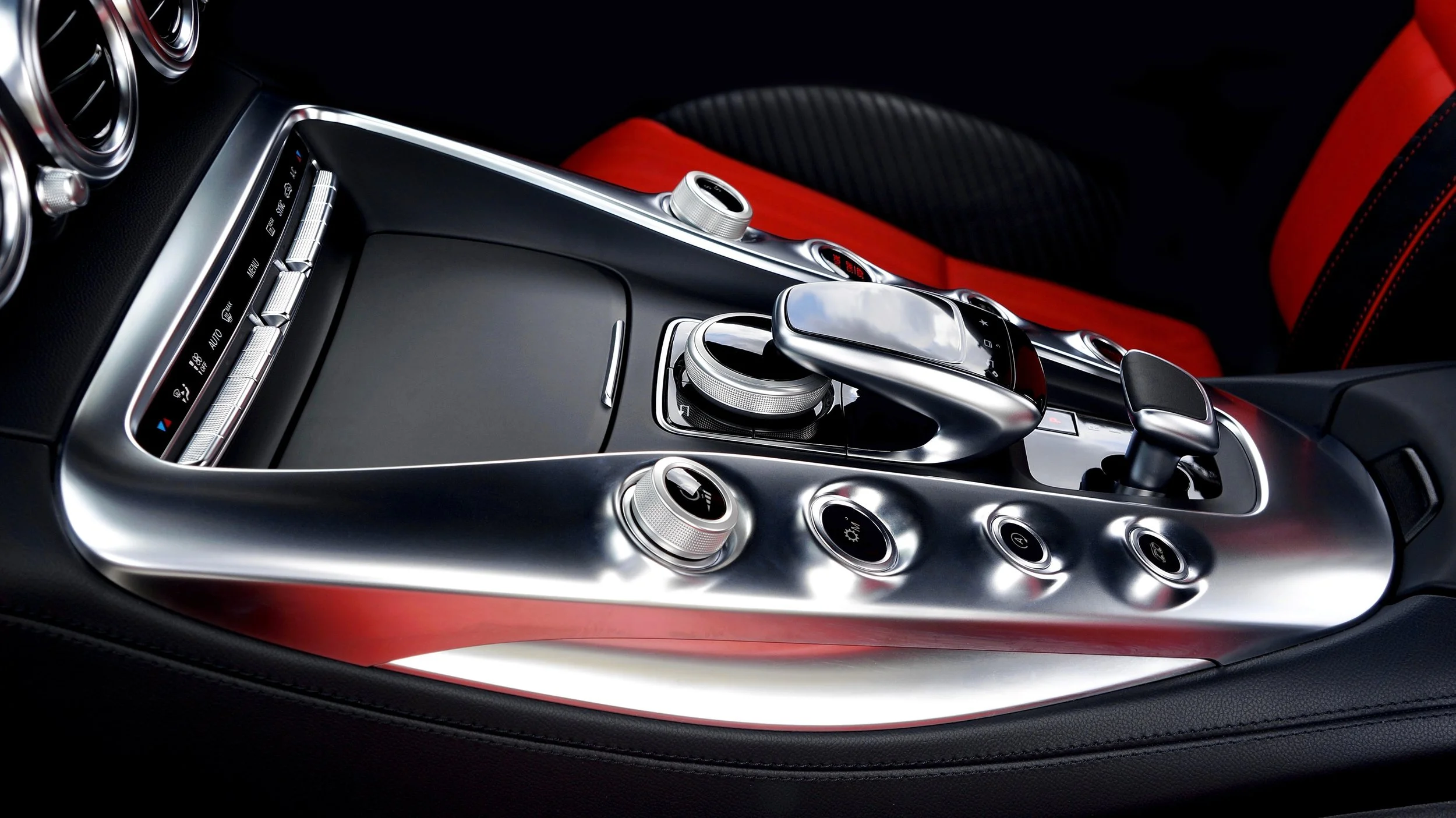 Luxury car interior center console with gear shifter, control knobs, and metallic accents.