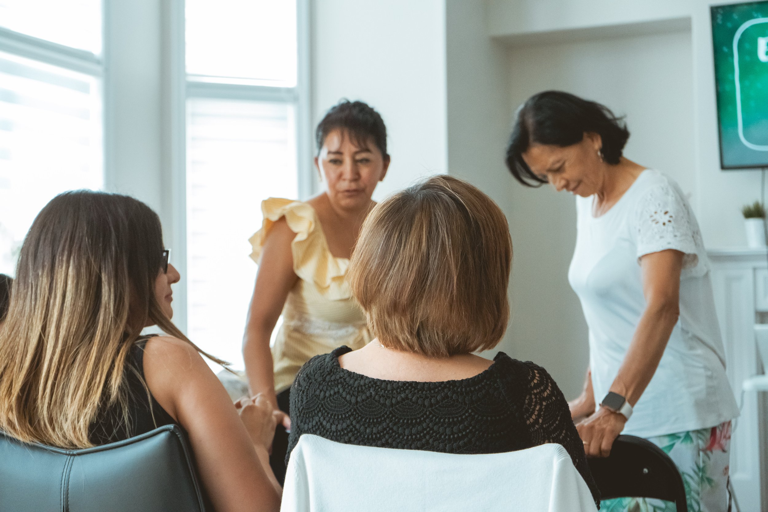 Group of women sitting and standing in a room during a meeting or discussion.