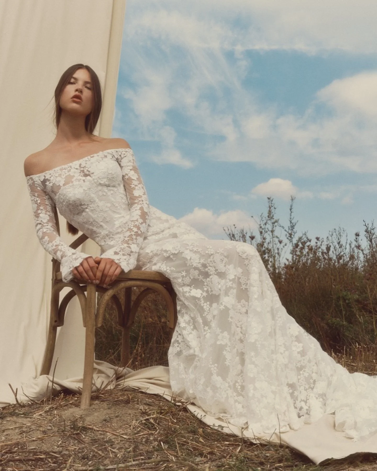 HALO 🤍✨ Strapless corseted sheath gown in beaded, laser-cut floral lace with a slim, elongated silhouette. Paired with a detachable bolero featuring long, fitted sleeves that create an off-the-shoulder illusion. Finished with buttons trailing to the