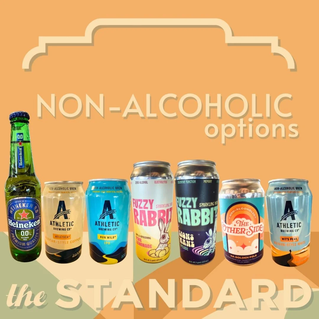 Collection of non-alcoholic drinks including a bottle of Heineken 0.0, several cans of non-alcoholic beer, and sparkling waters with colorful labels on a graphic background with the text "Non-Alcoholic options the STANDARD."