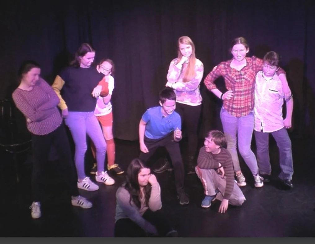 Group of children and teens on stage posing and having fun during a performance or rehearsal.