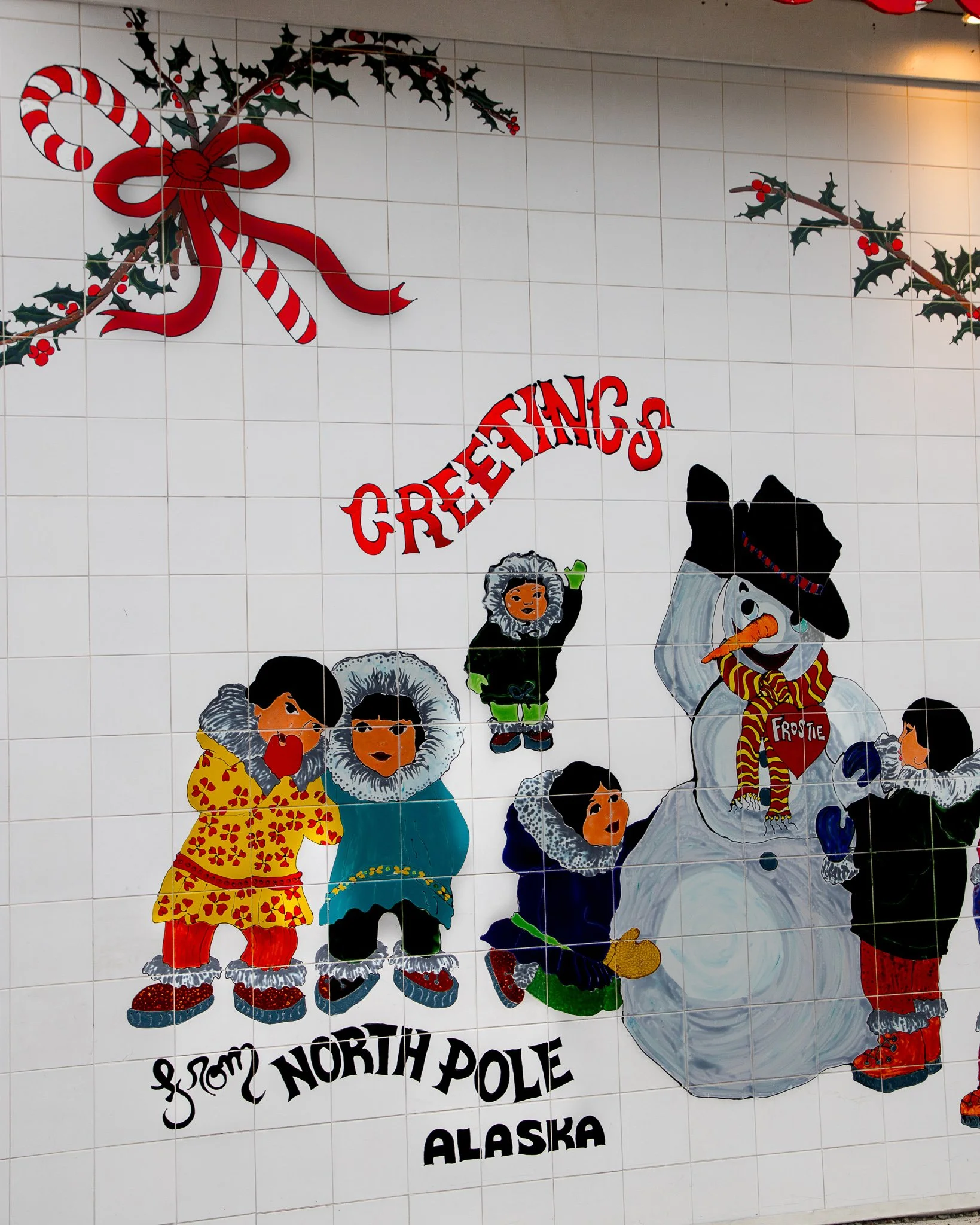 “Greetings from North Pole, Alaska” mural featuring children, a snowman, and festive winter imagery painted on the Santa Claus House