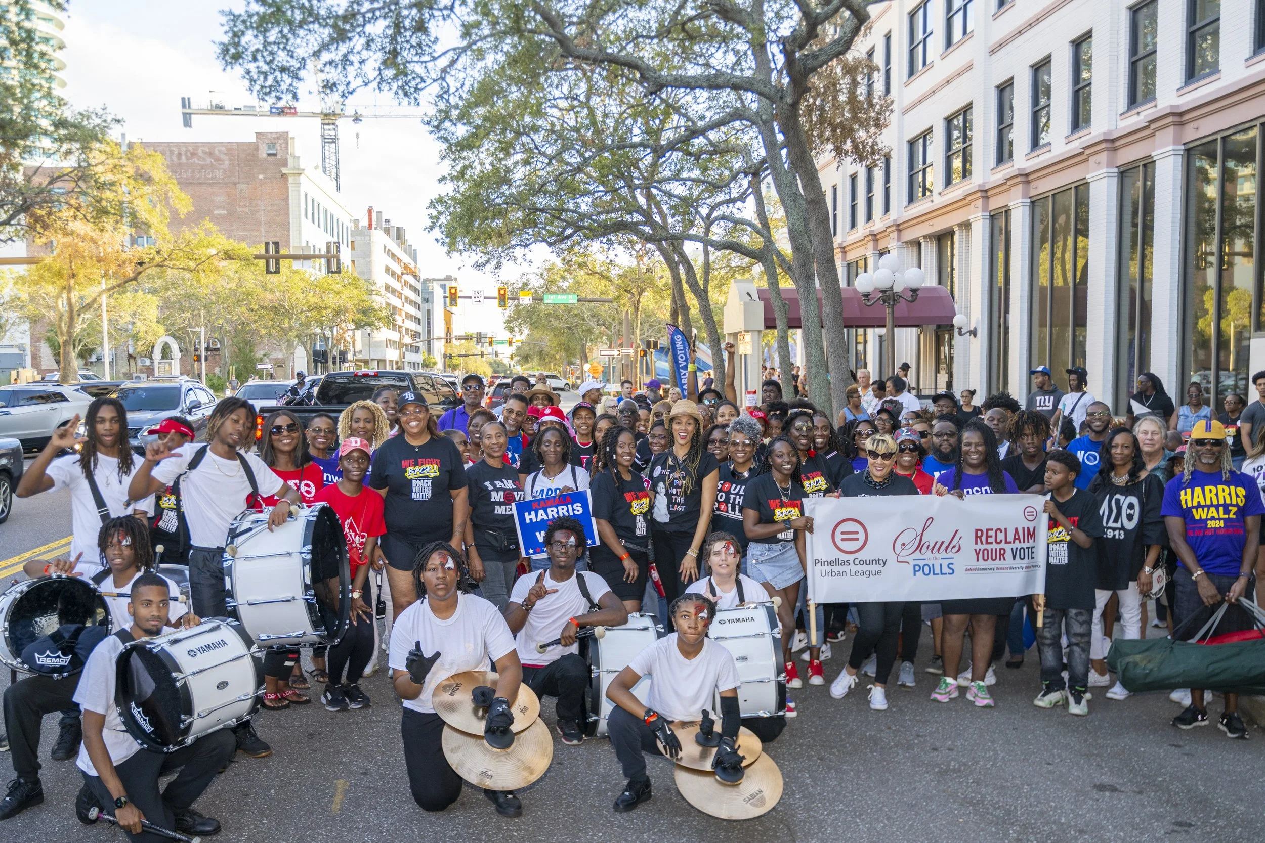 Large group of community members marching in downtown St. Petersburg holding a Pinellas County Urban League “Souls to the Polls – Reclaim Your Vote” banner with youth drummers in front.