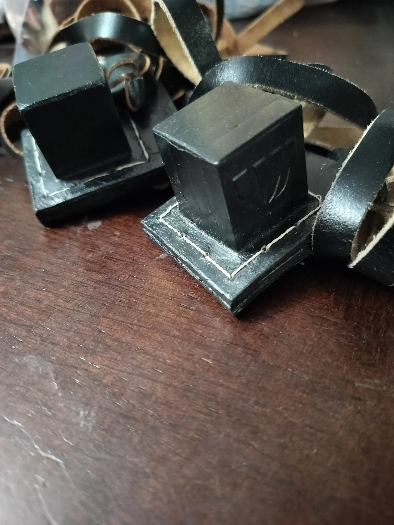 Close-up of black leather straps and black plastic square buckles on a wooden surface