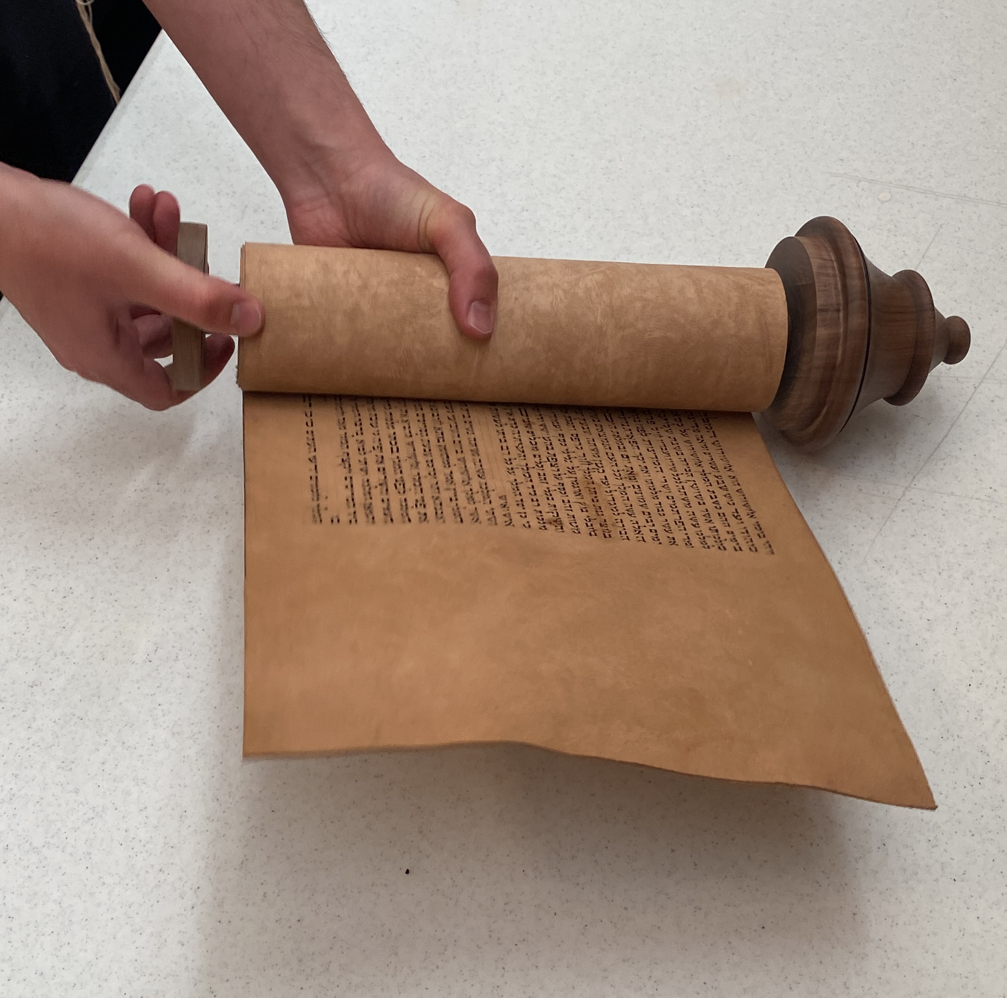 Person flipping through an ancient scroll with printed text on parchment.