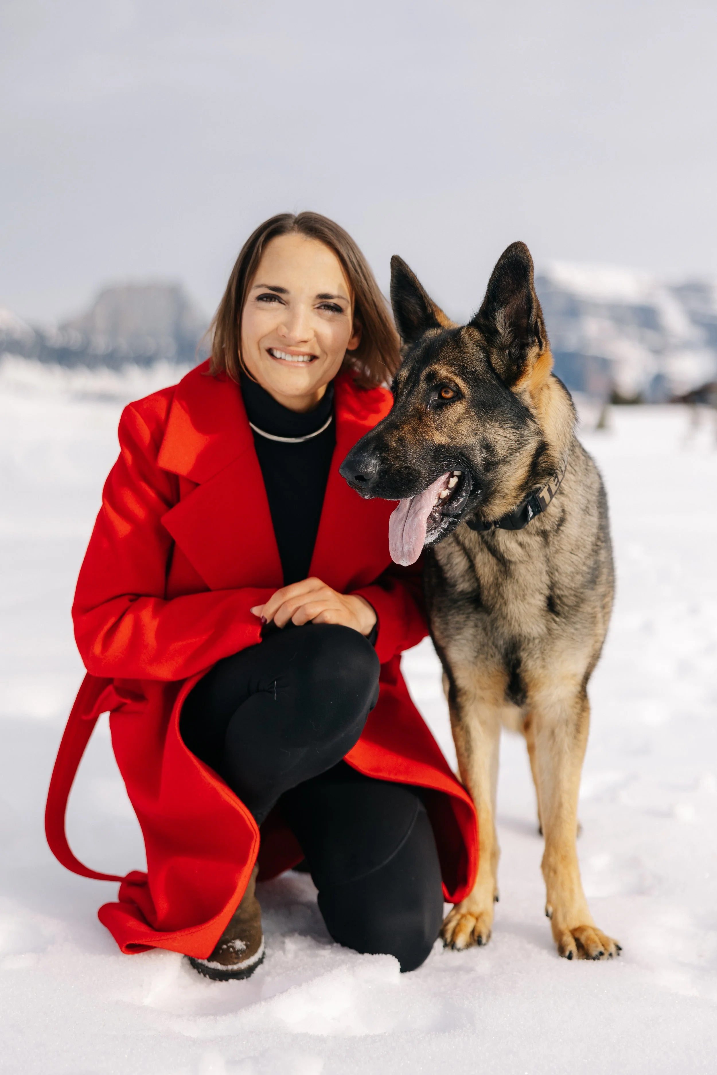 Woman in red coat with personal protection dog German Shepherd.