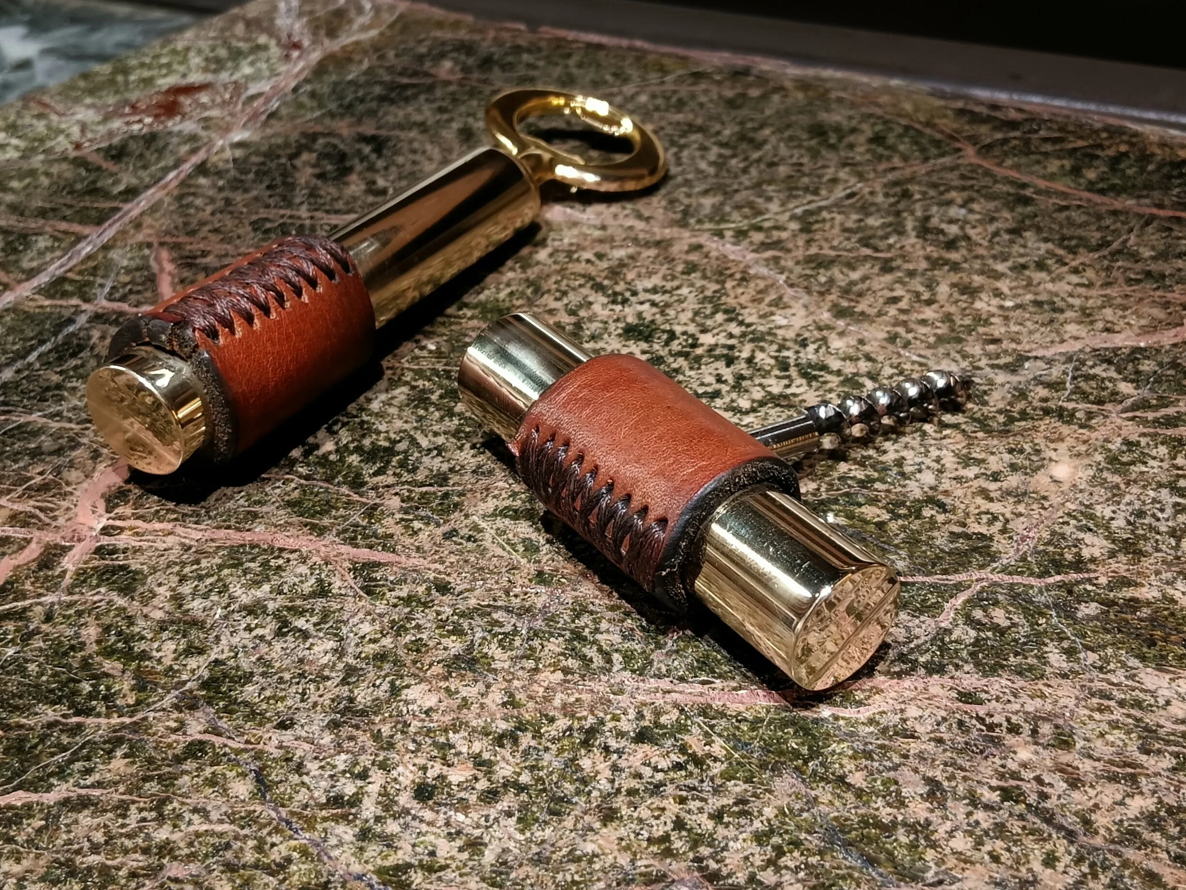 A  bottle opener & corkscrew in brass with handstitched  brown  leather  detailing