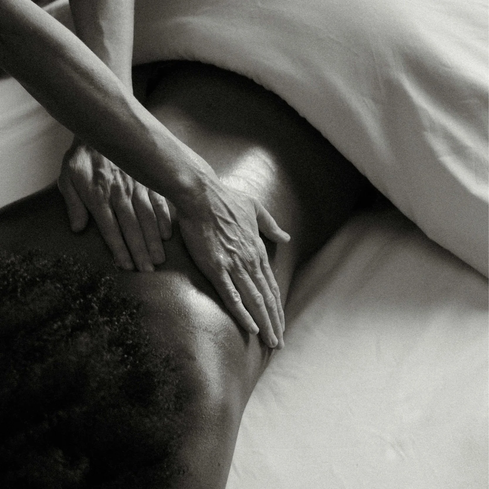 Black and white photograph of a person's arm and hand resting on a surface, with the hand extended and fingers relaxed.