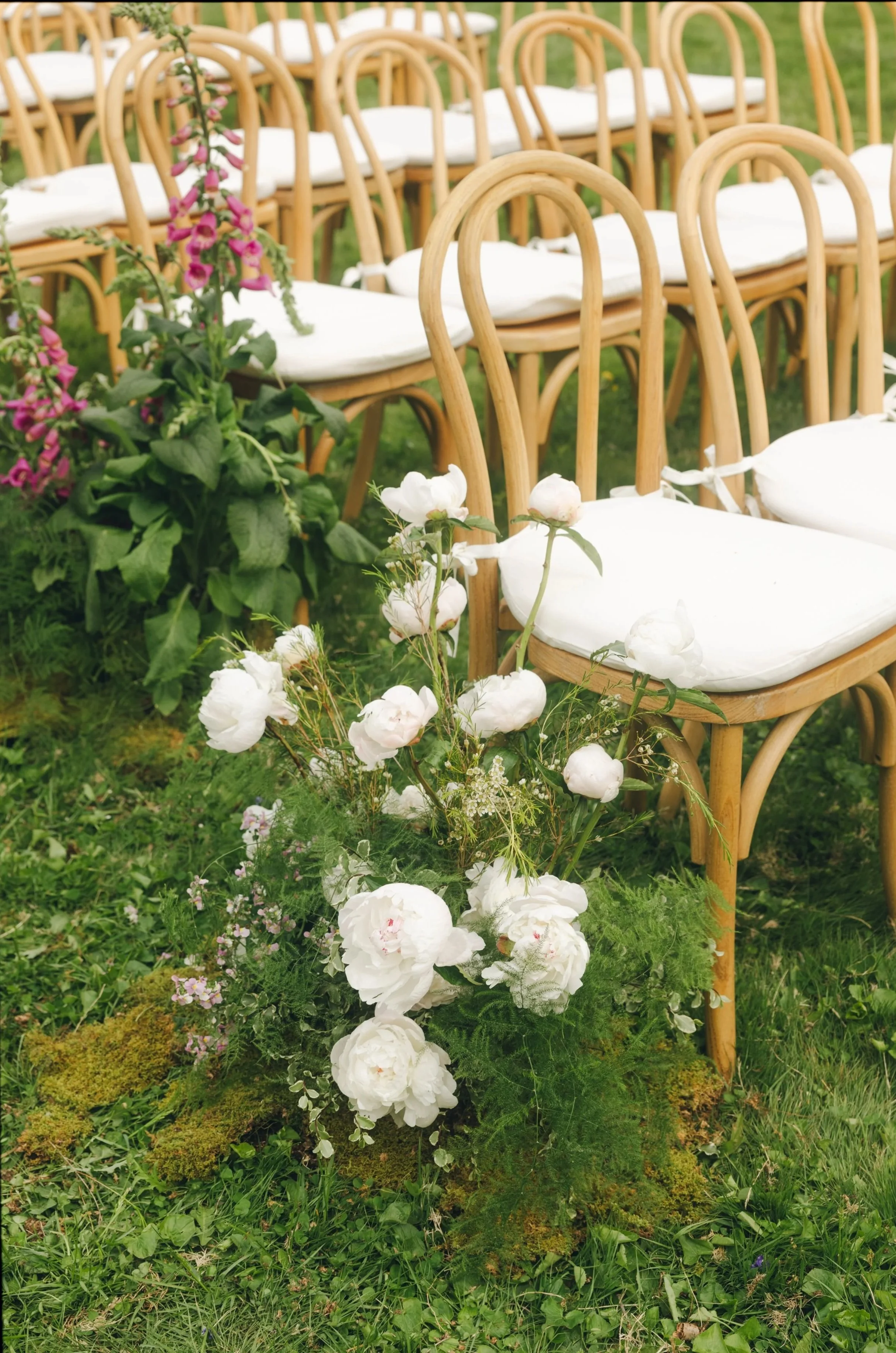 Romantic spring outdoor wedding lined with foral aisle markers of white peonies and pink foxgloves. Rows of bentwood chairs. Hudson Valley, New York Wedding Florist.