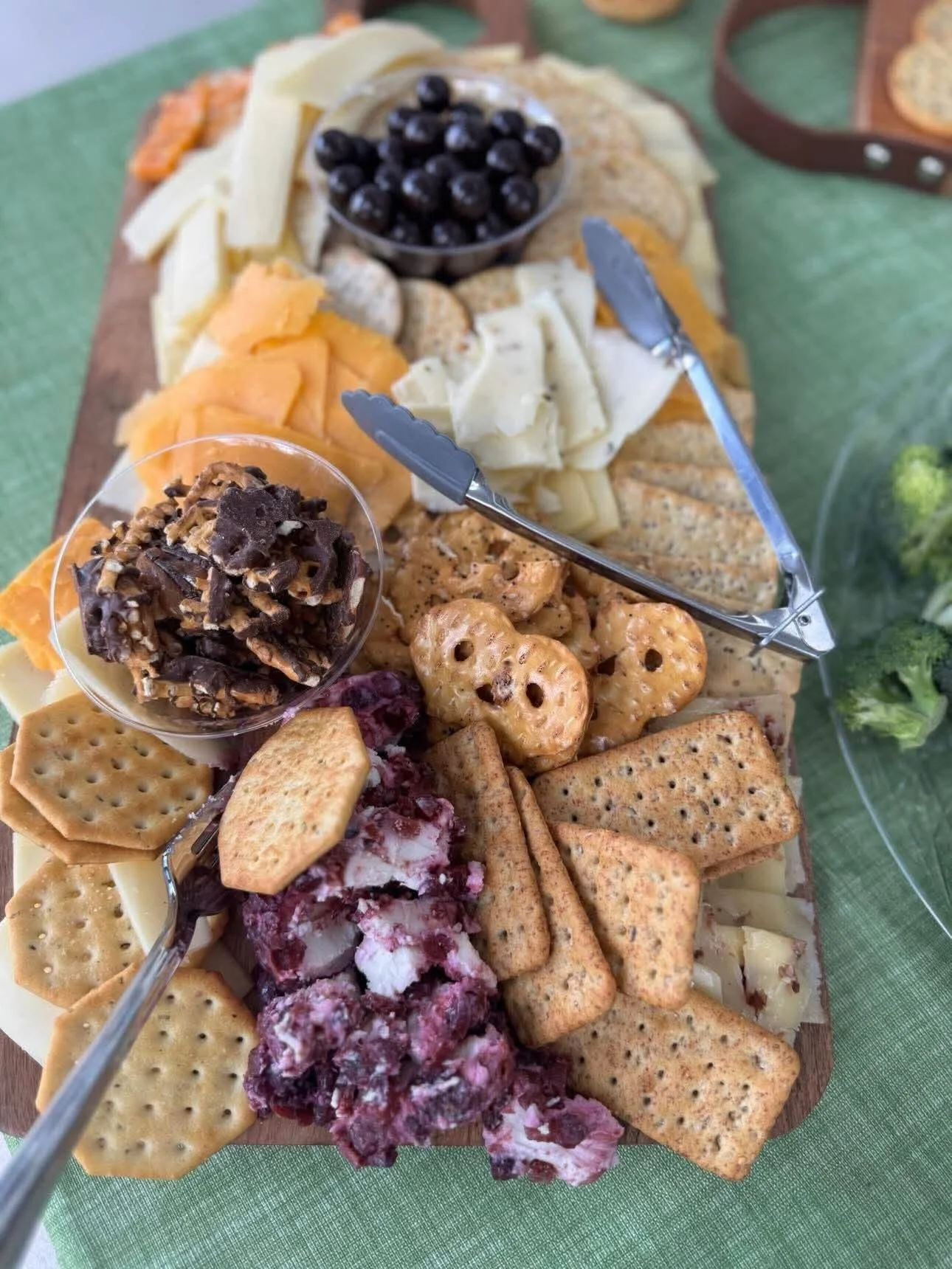 A cheese and cracker platter with grapes, berries, and assorted crackers on a wooden board.