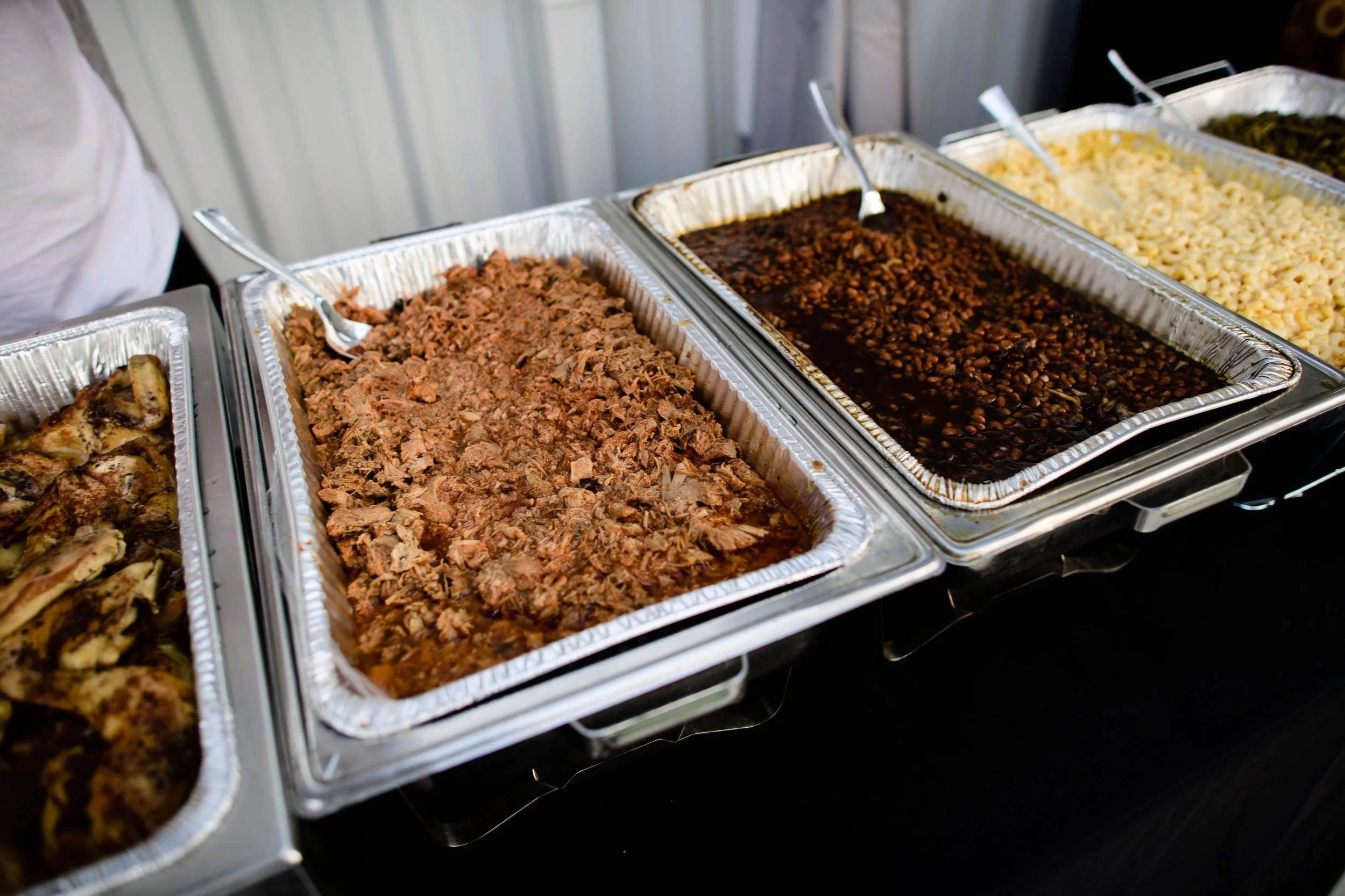 Chafing dishes filled with shredded beef, dark beans, and pasta.