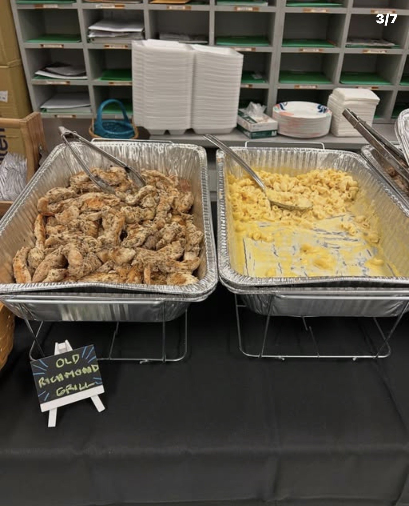 Buffet table with trays of cooked meat and macaroni and cheese at a food service event.